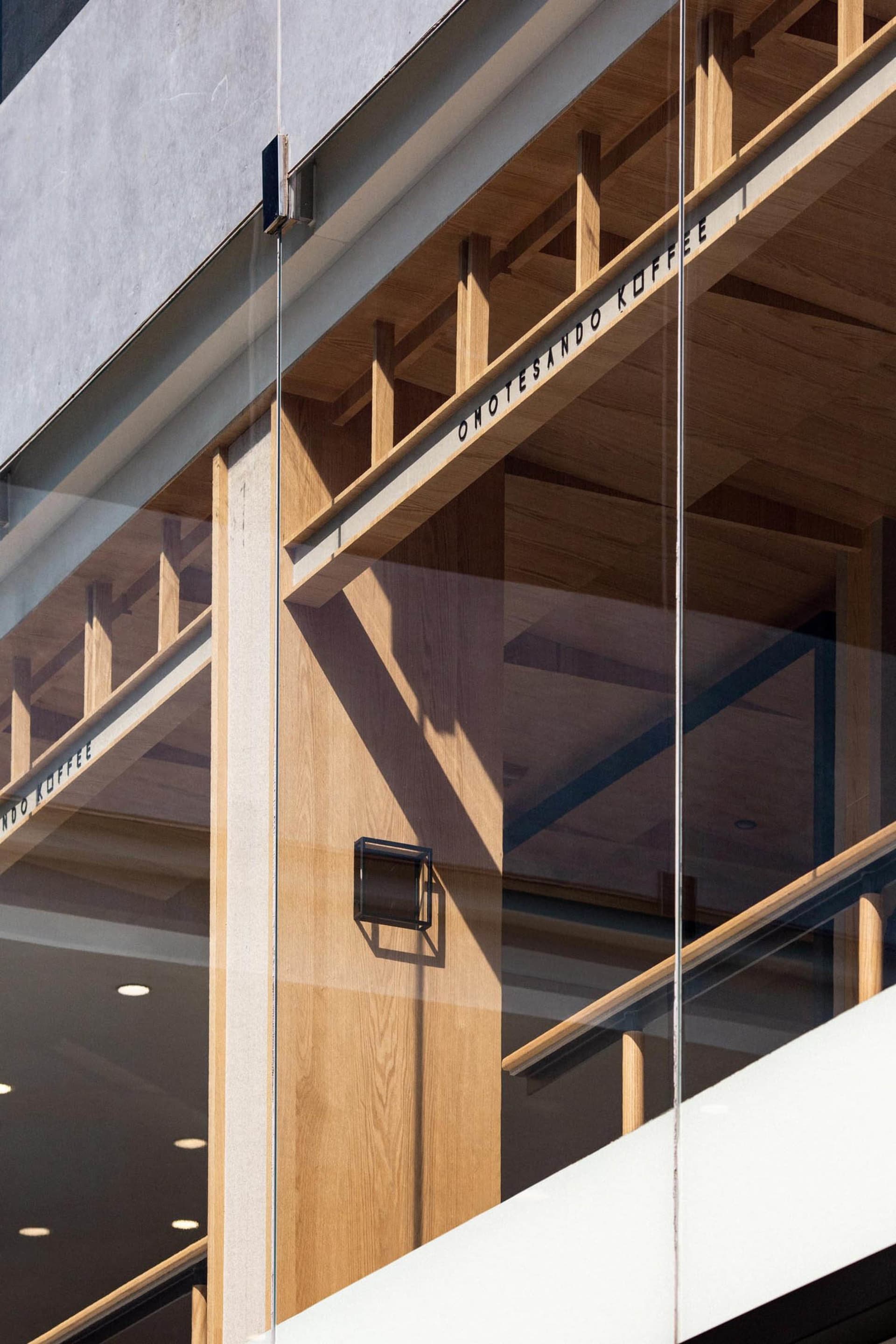 A modern building with a glass wall and wooden panels on its facade, showcasing the contrast between the two materials and the natural light entering through the glass wall