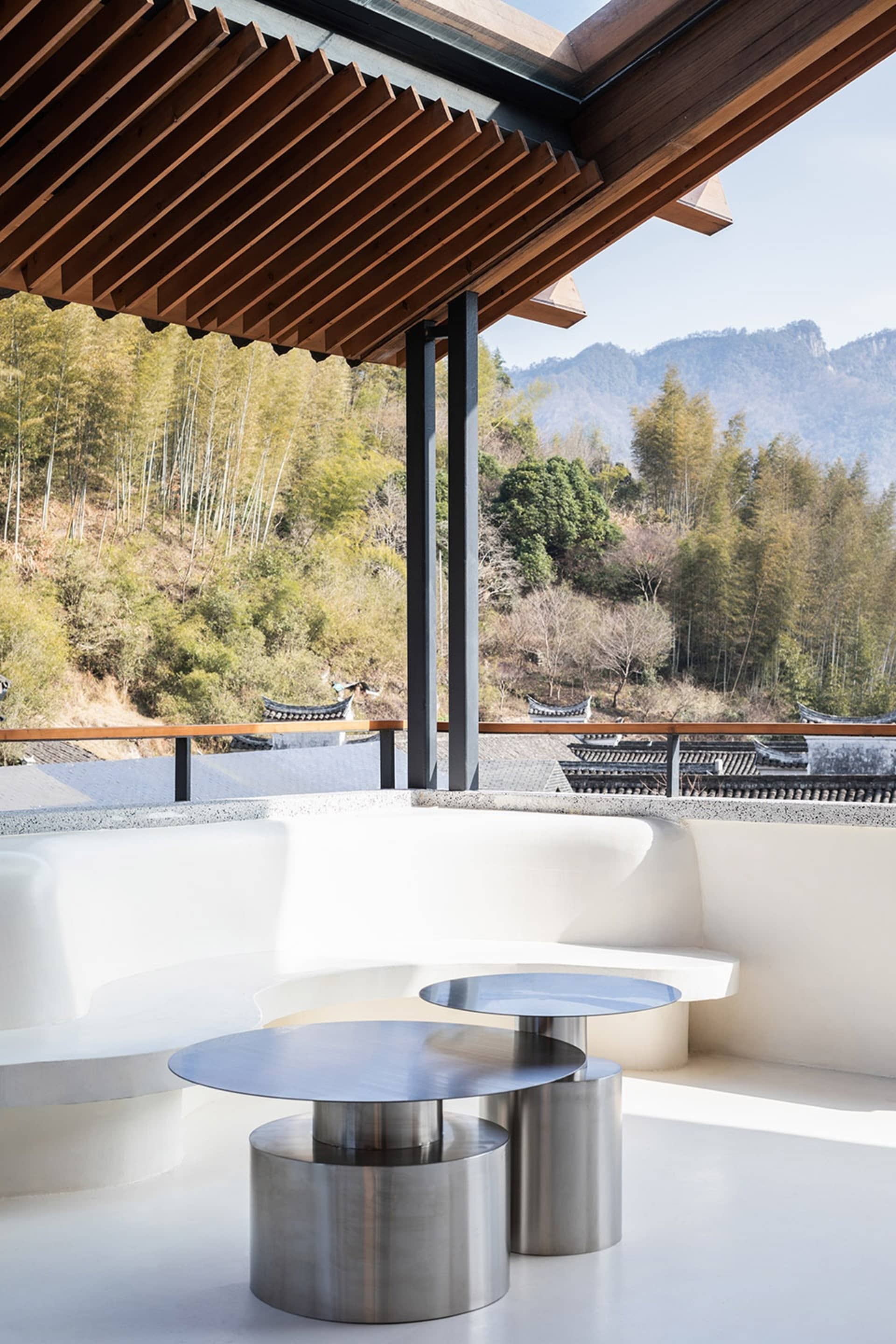 Open living space with a white couch, two dining tables, and a window overlooking a mountain view, bathed in natural light