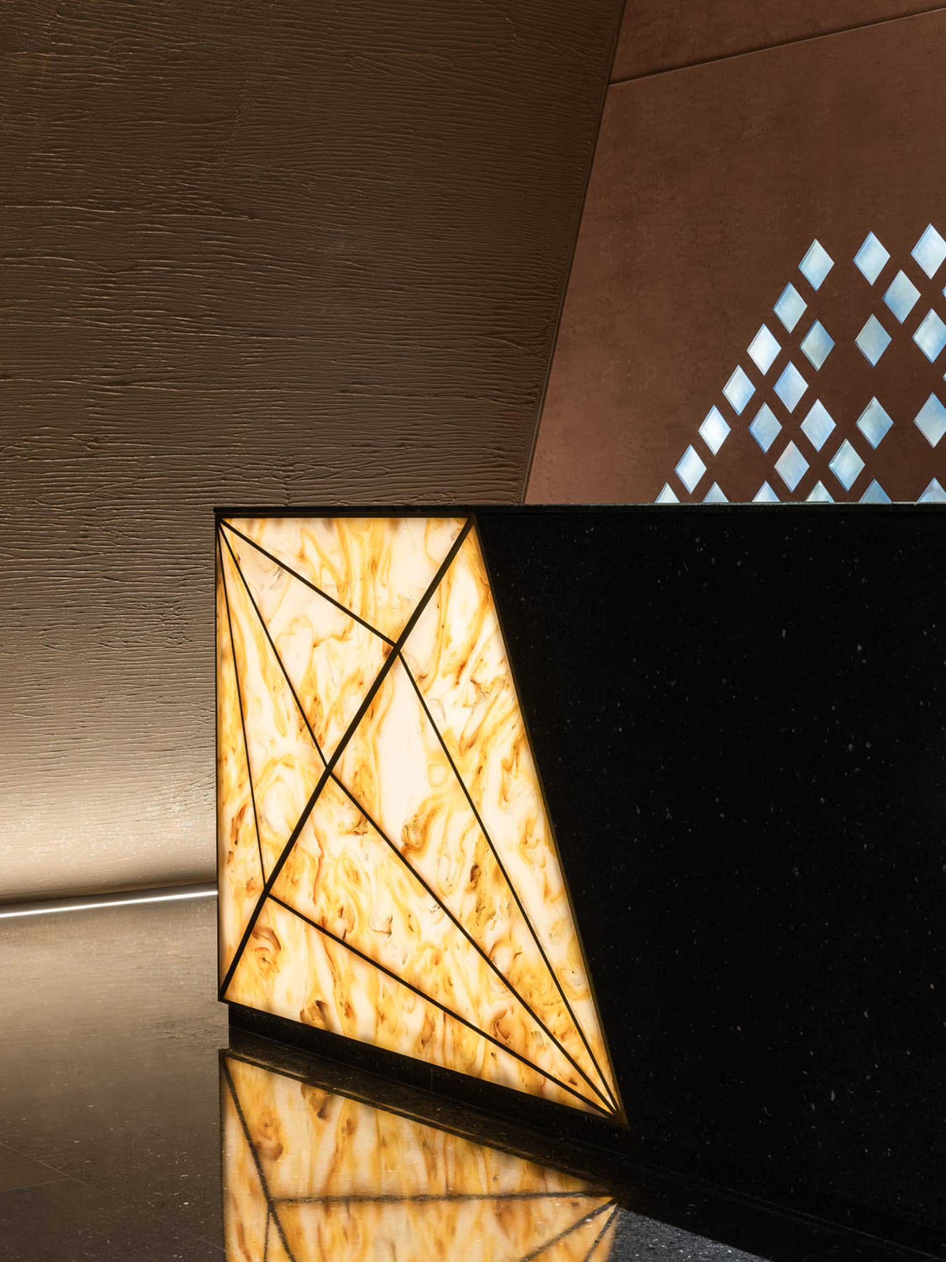 A luxurious hotel lobby interior featuring a black marble countertop with a yellow and brown pattern, two triangular shapes, and a sophisticated atmosphere