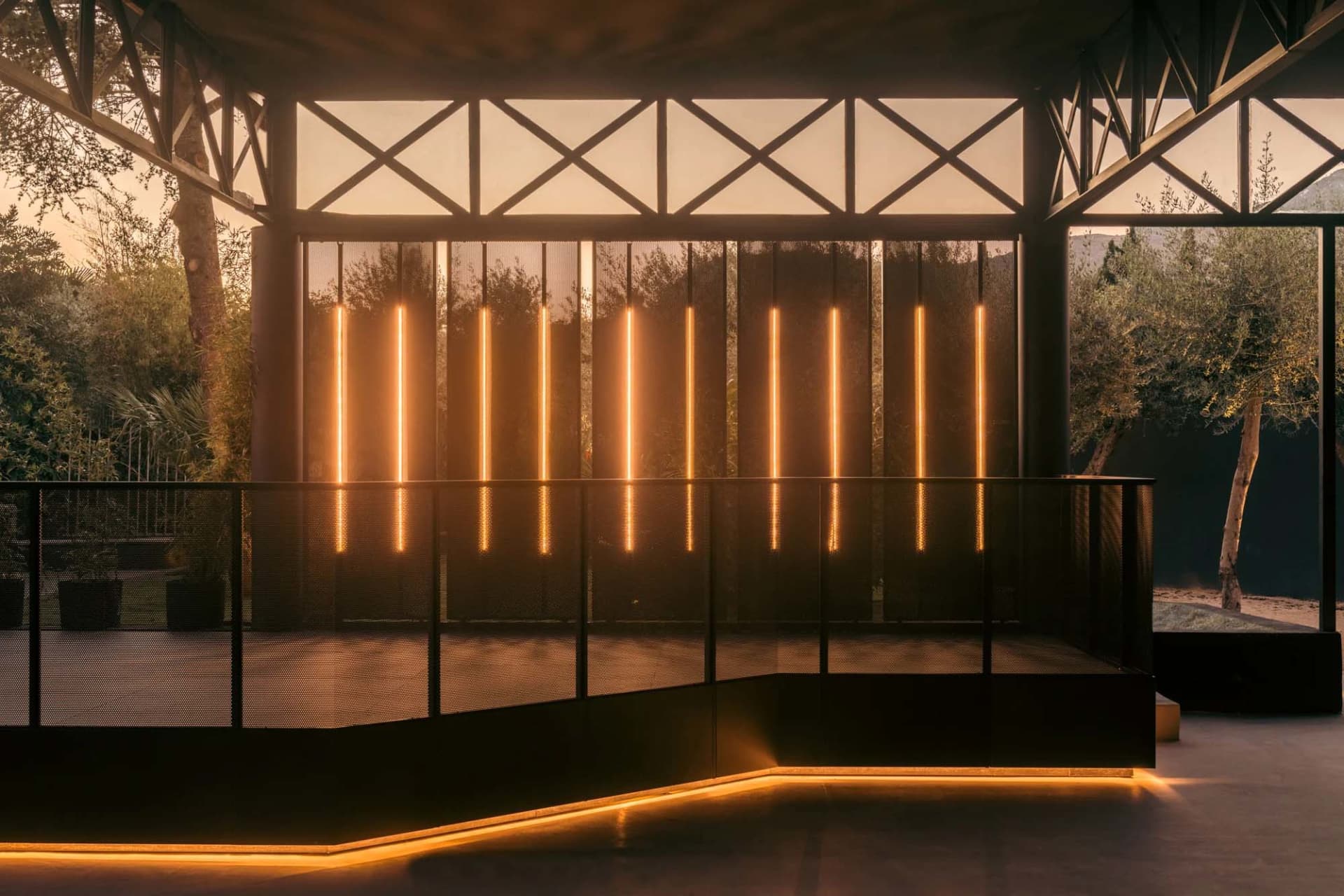 A modern building with a concrete facade, black window frames, and yellow lit windows, creating a stylish and warm atmosphere