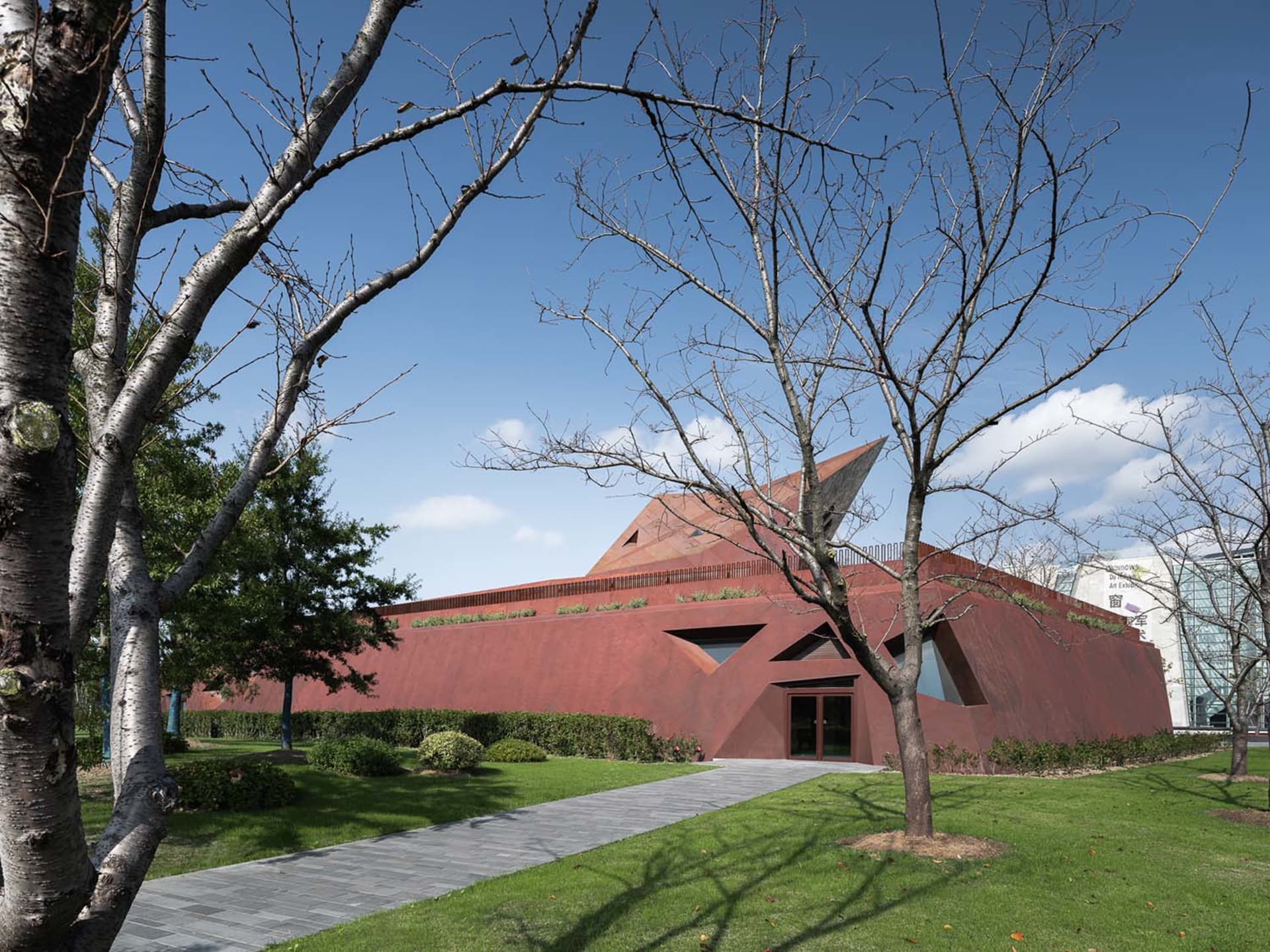 A modern house with a red roof, surrounded by trees, in a natural setting
