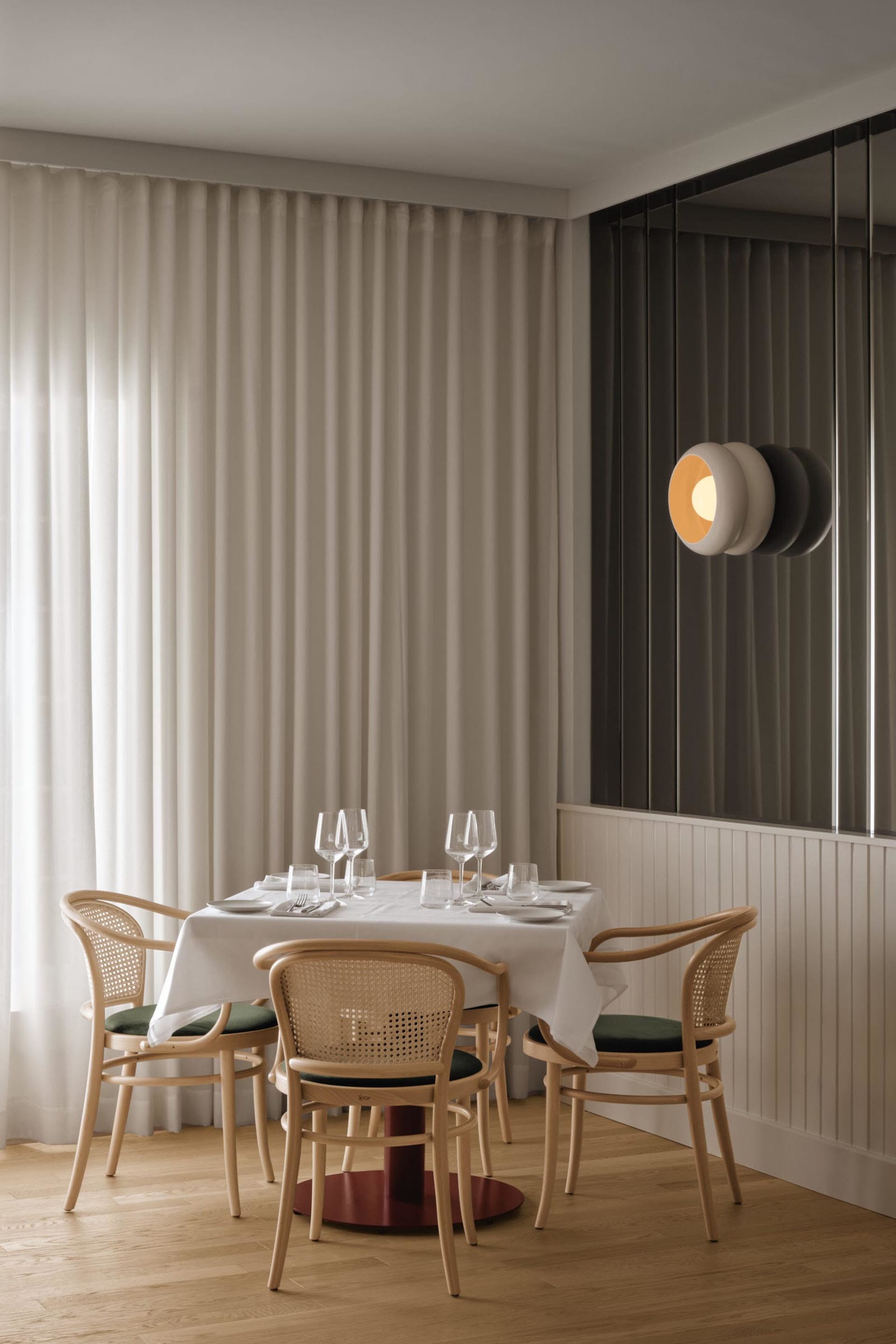 A formal dining area with a large white table surrounded by chairs, wine glasses, and a clean, organized atmosphere
