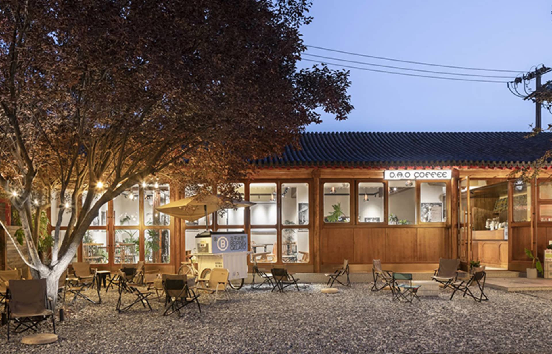 Cozy modern coffee shop with a wooden exterior, patio seating, and a dining area with a table and chairs