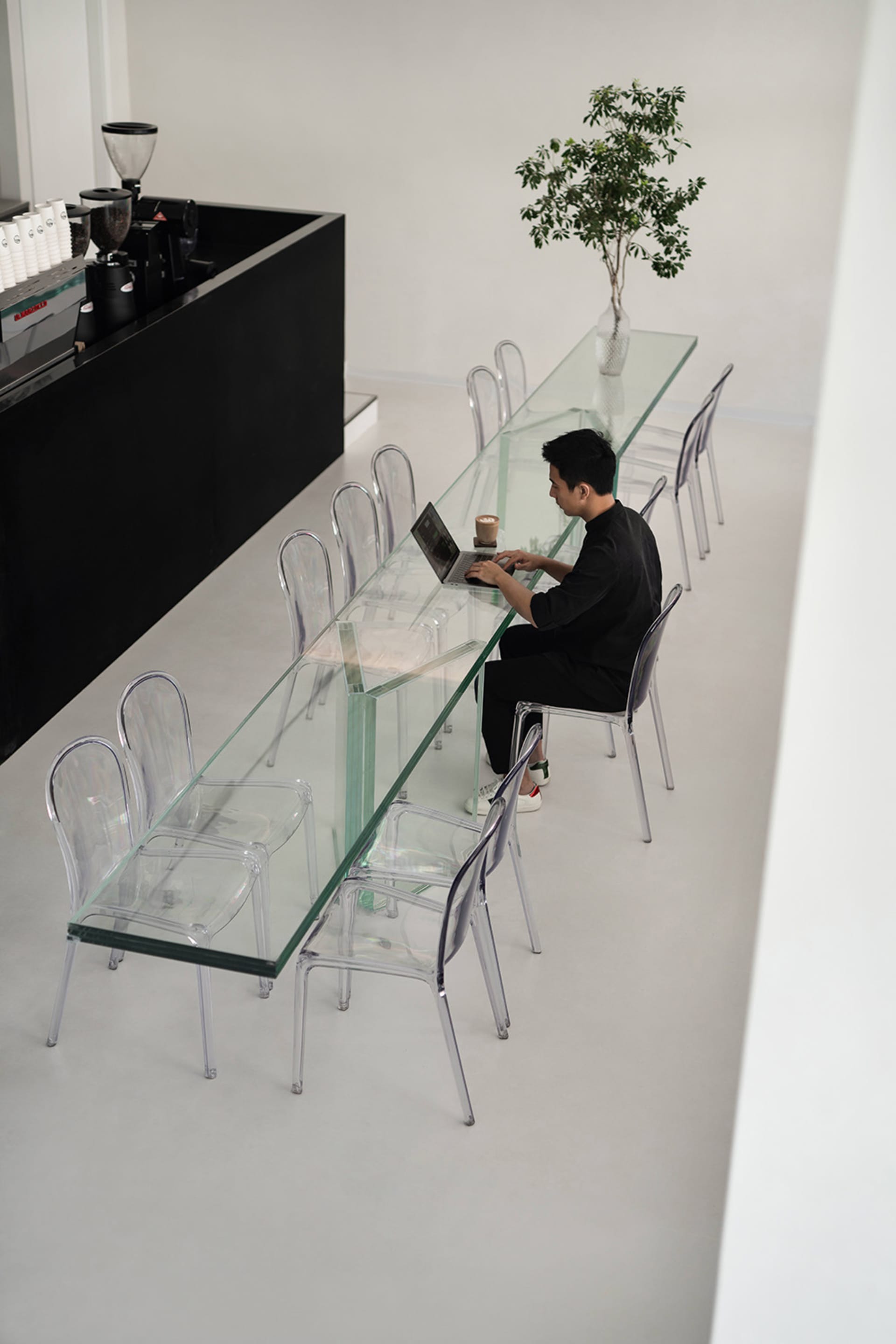 玻璃桌休閒餐廳空間，配有椅子，有人使用筆電並坐在附近