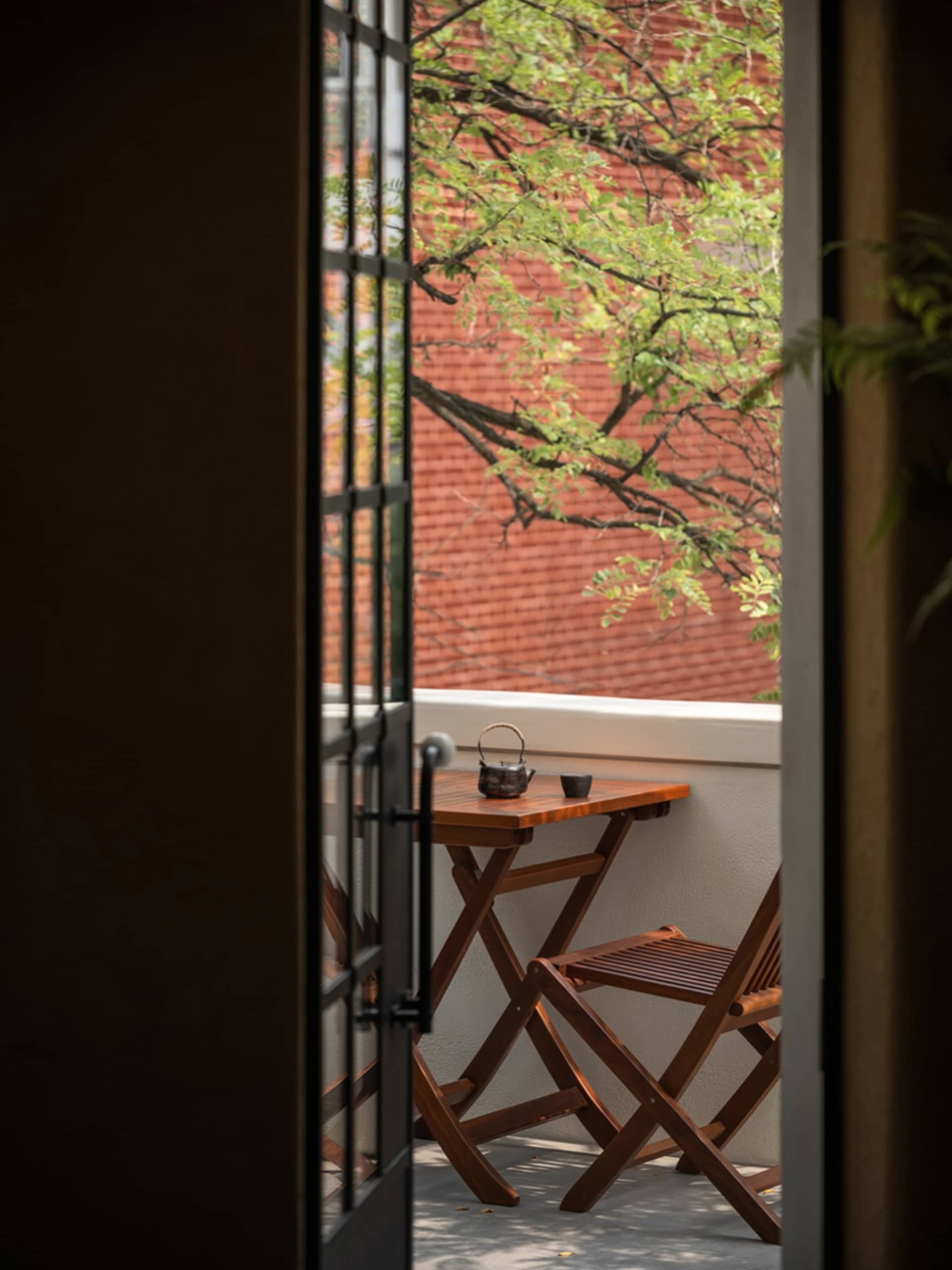 A residential outdoor dining area with a wooden table and chairs, set in a sunny location