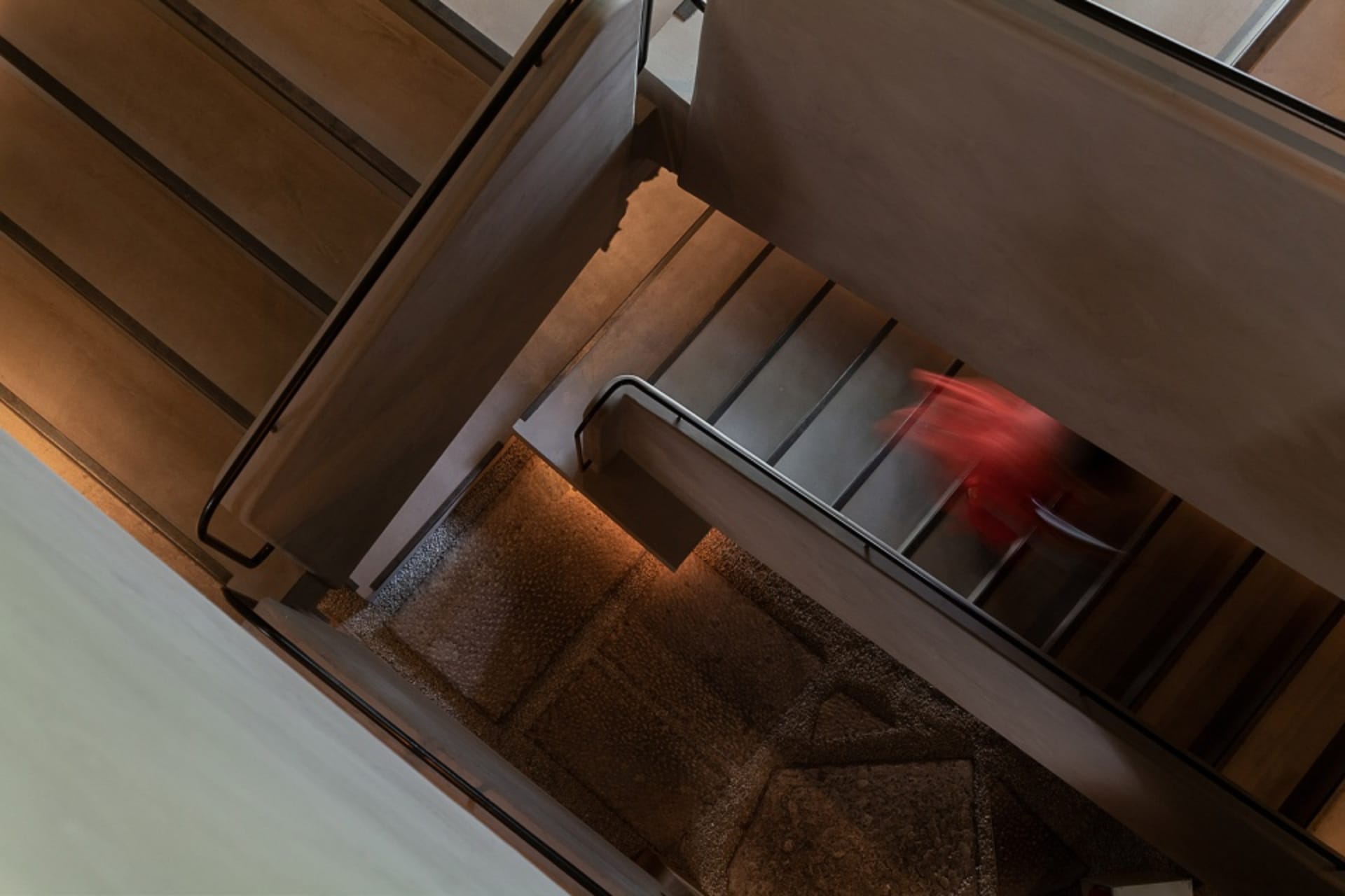 A rendered architectural scene of a stairwell with concrete stairs, suggesting a sense of depth and complexity within the structure