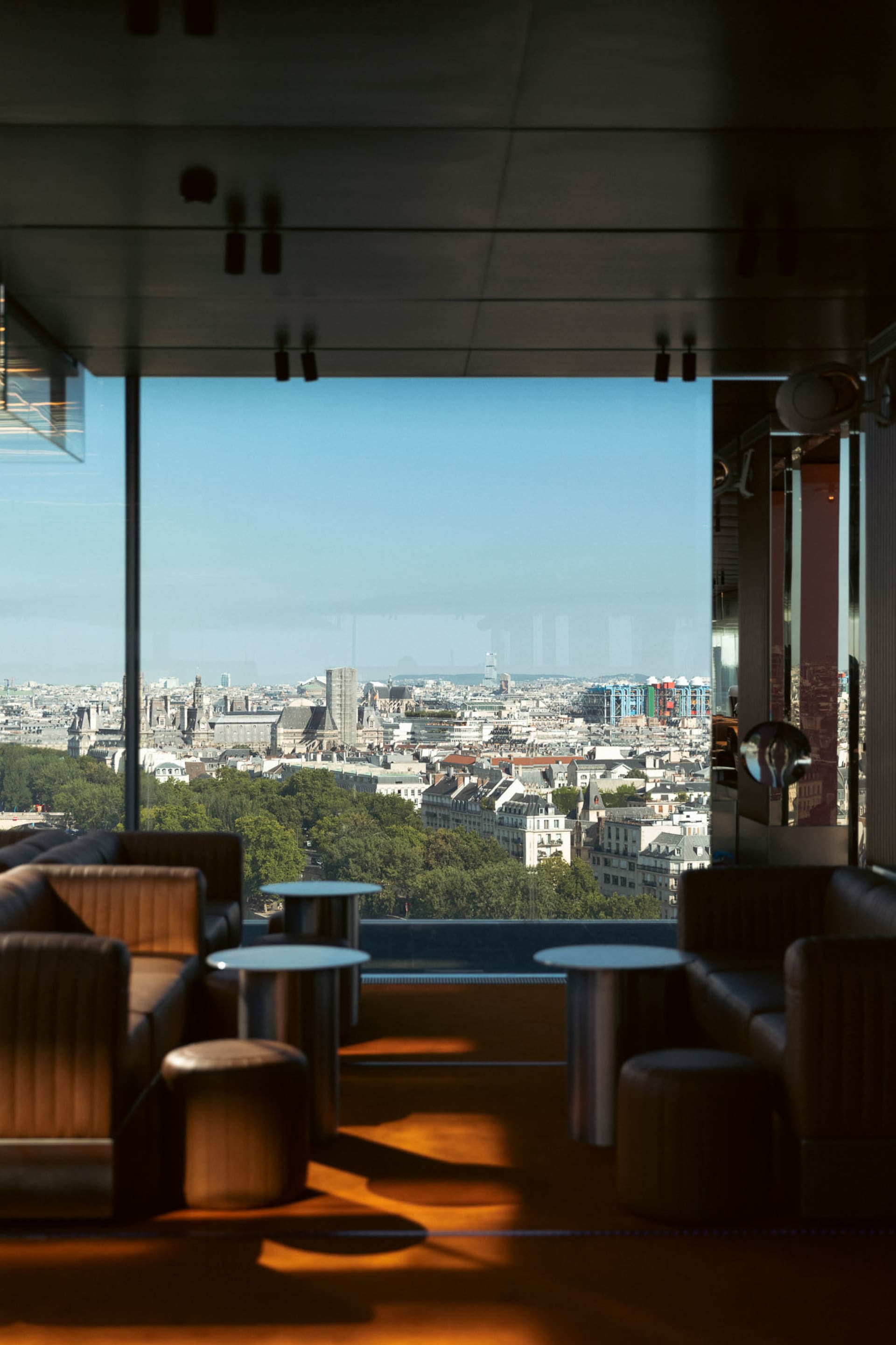 建築頂樓餐廳擁有玻璃牆，提供全景城市美景、舒適座椅與高級設計元素