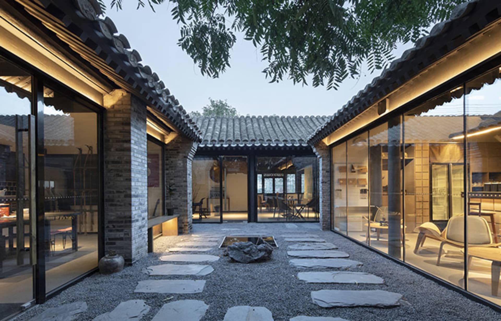 A serene Asian-style house with a courtyard area featuring a rock garden, stone walls, and tiled roofs