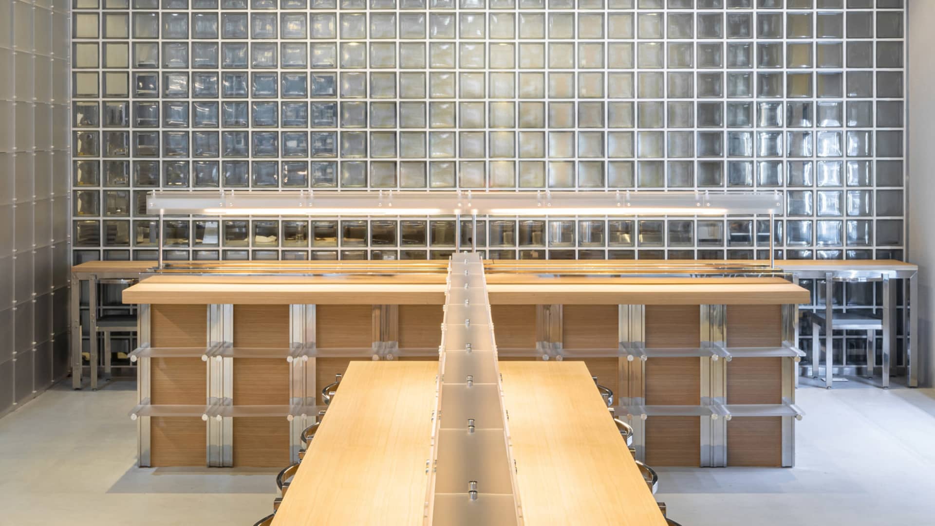 A large dining hall with wooden tables and chairs arranged in rows, surrounded by numerous dining tables and chairs, creating a warm and inviting atmosphere