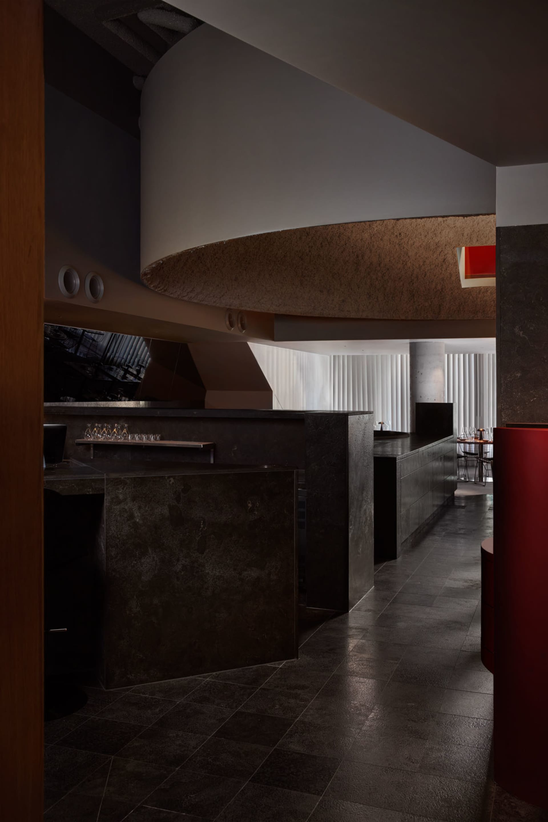 A modern bar area with a counter, dining table, and chairs, surrounded by grey walls and contemporary decor