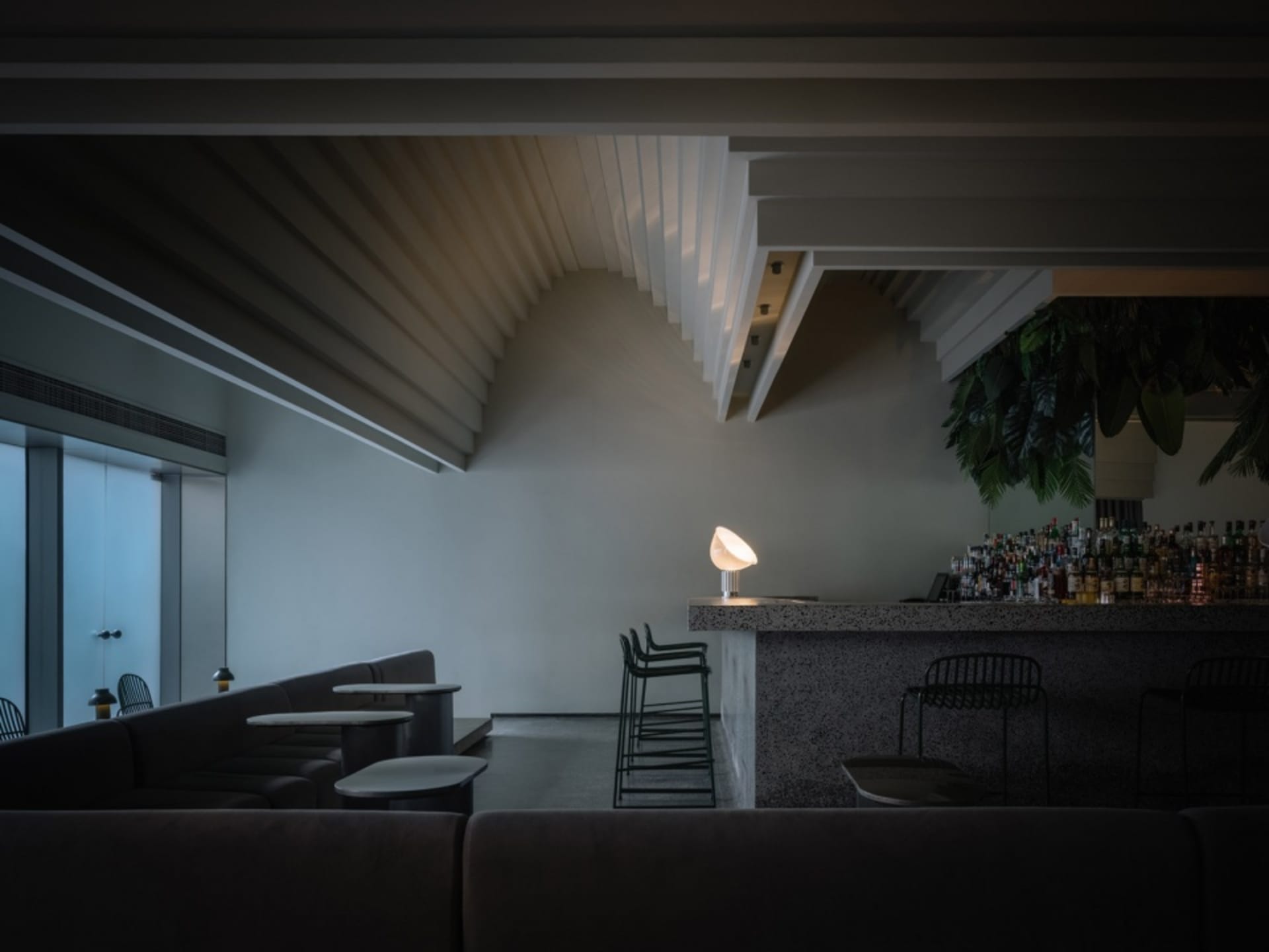 An empty bar area with a marble countertop and two chairs, creating a sophisticated and elegant atmosphere
