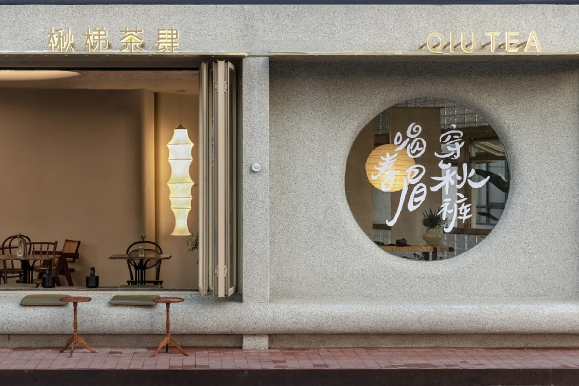 A modern Asian storefront with a large circular window, comfortable seating, and a stylish interior