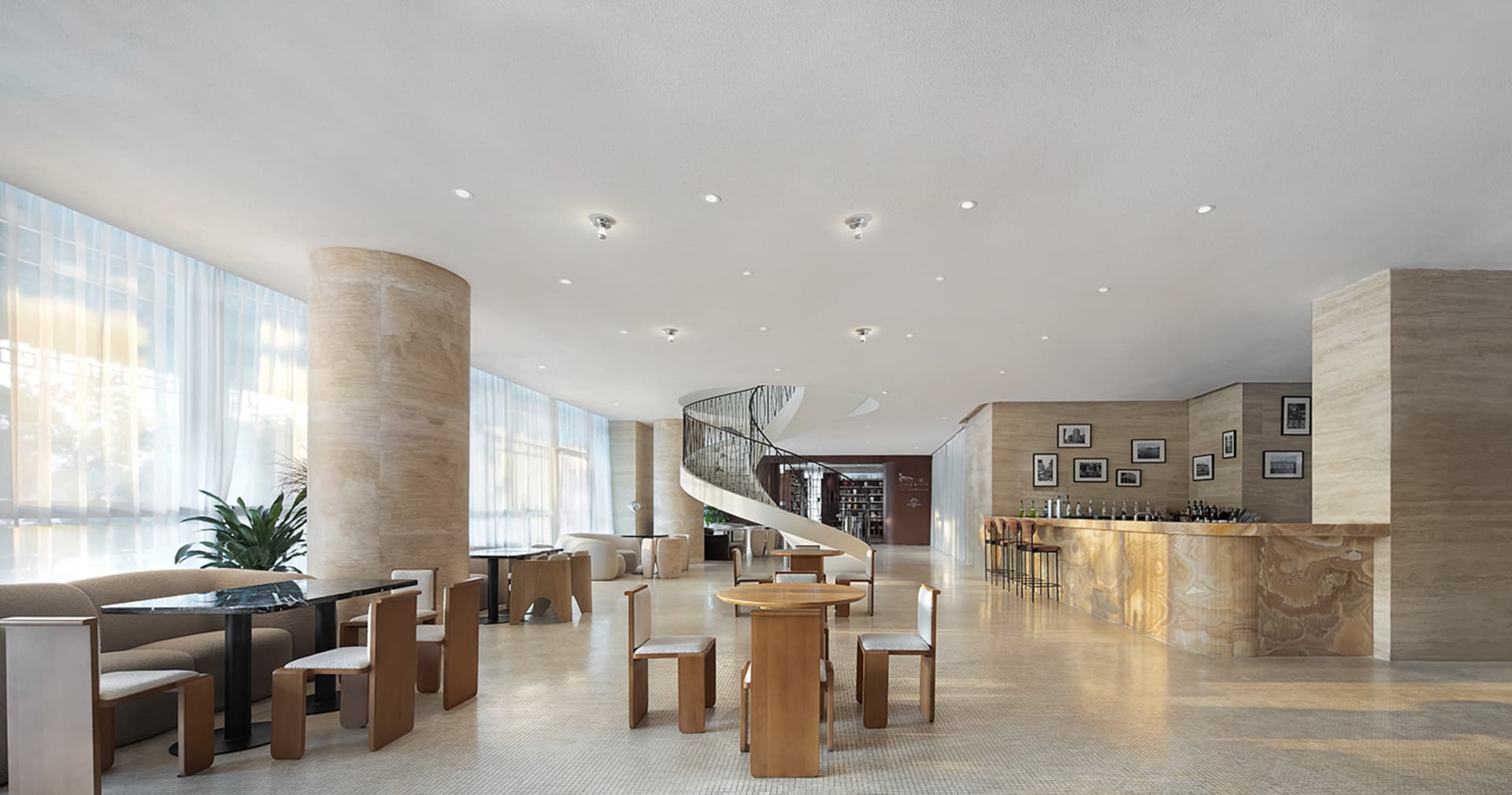 Modern lobby with a spiral staircase, chairs, and dining tables, surrounded by clean lines and minimalist decoration