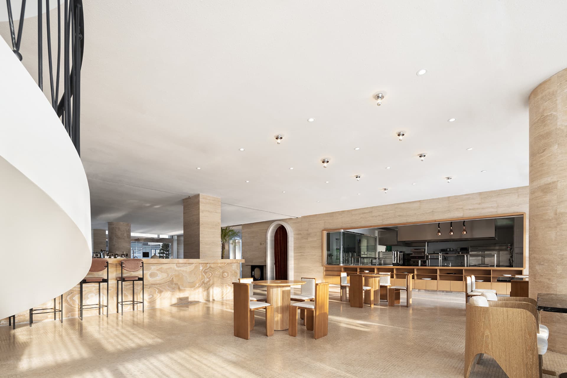 現代餐廳內部，木質餐桌、石材牆面與金屬點綴，自然光線充沛，舒適座椅