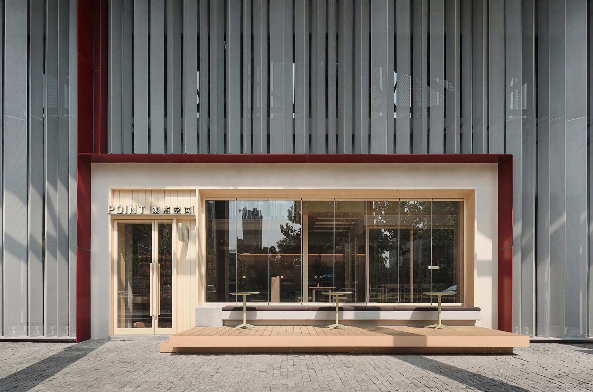 A modern building with a large window and exterior seating area featuring benches in a welcoming atmosphere