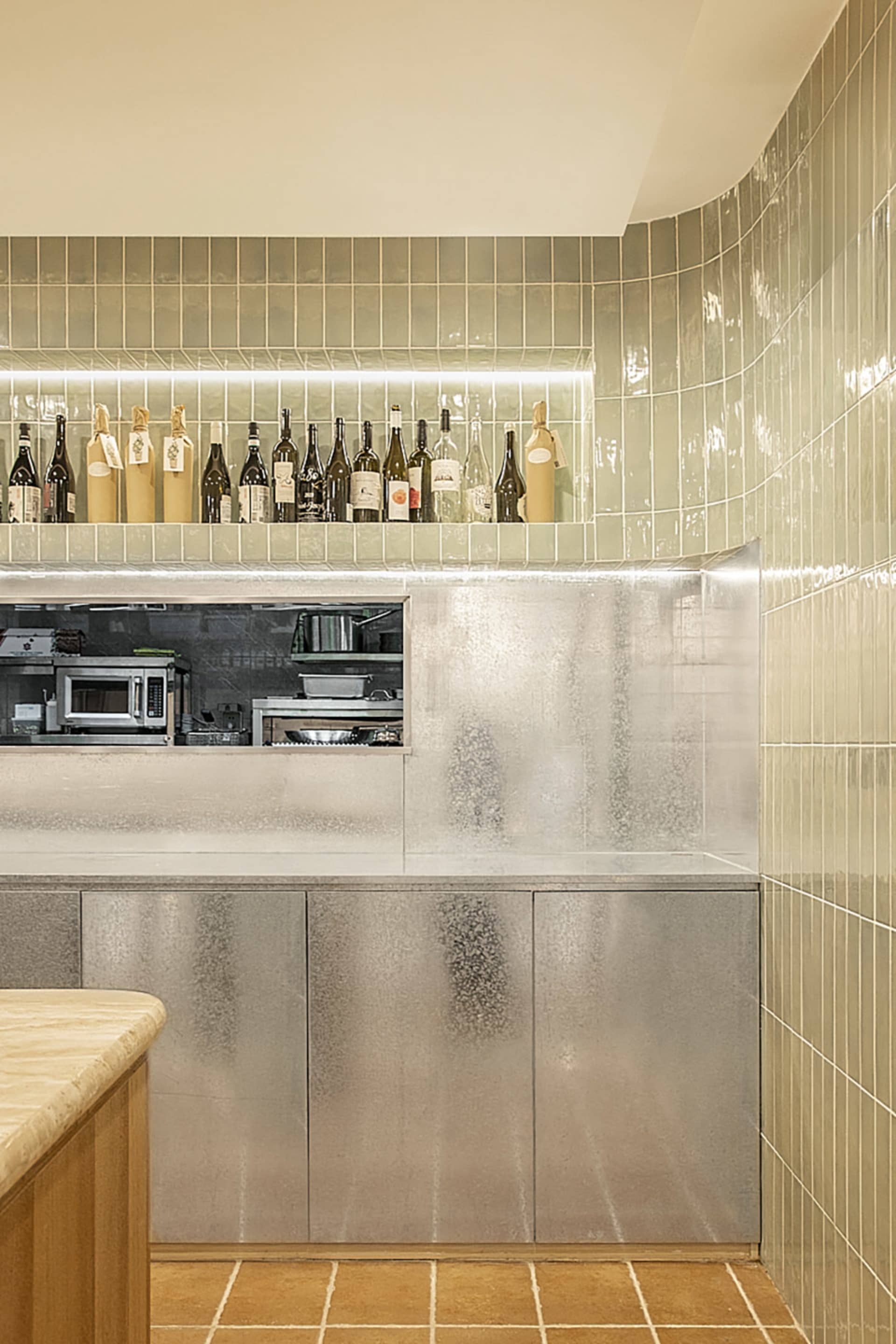 A restaurant-style kitchen counter with wine glasses, bottles, and bowls arranged on a sleek surface