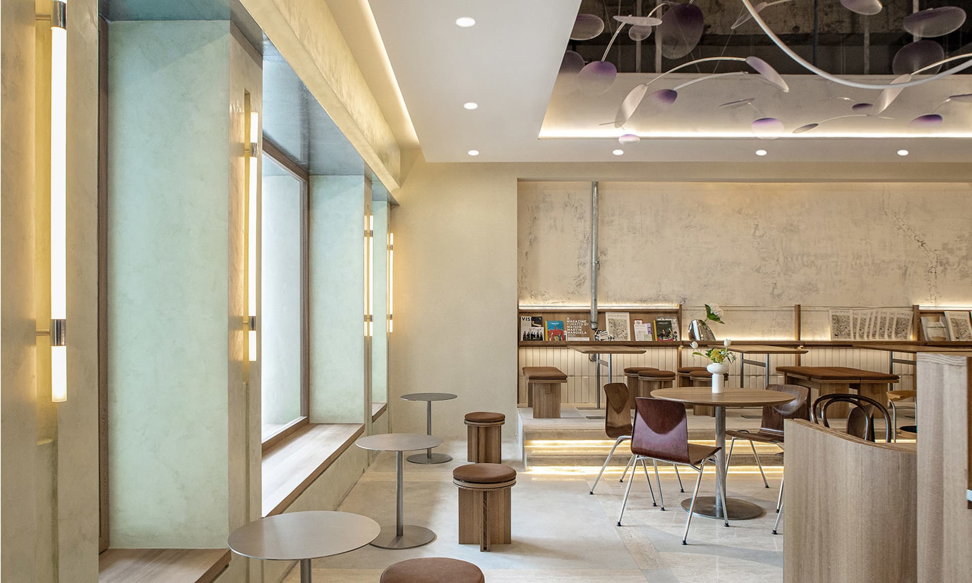A modern restaurant dining area with tables, chairs, potted plants, artwork on the walls, and a welcoming atmosphere