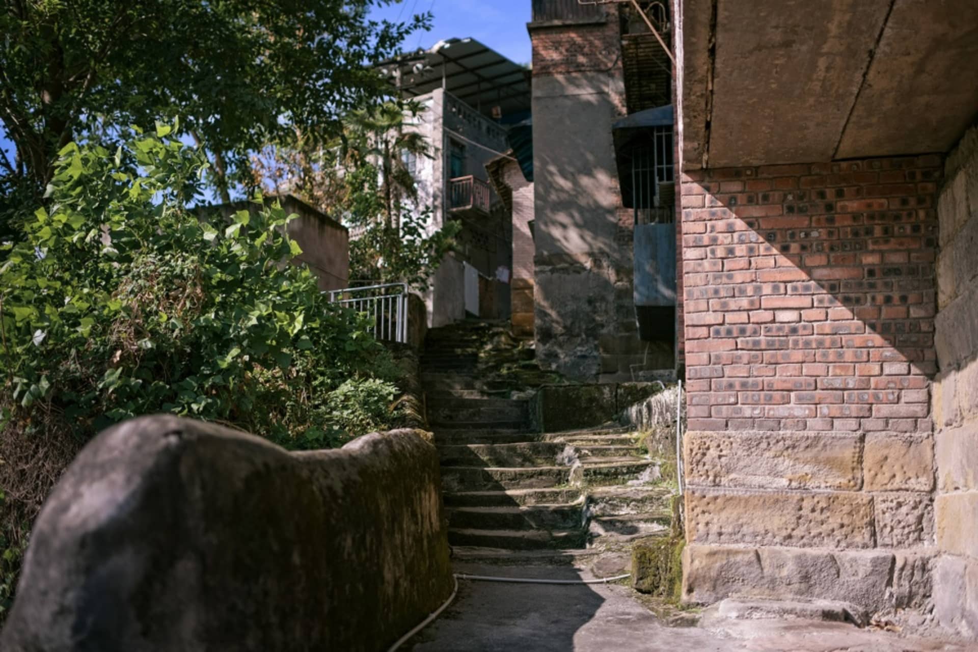 A historic stone building with worn stone steps and a metal railing, set against a possibly park-like background