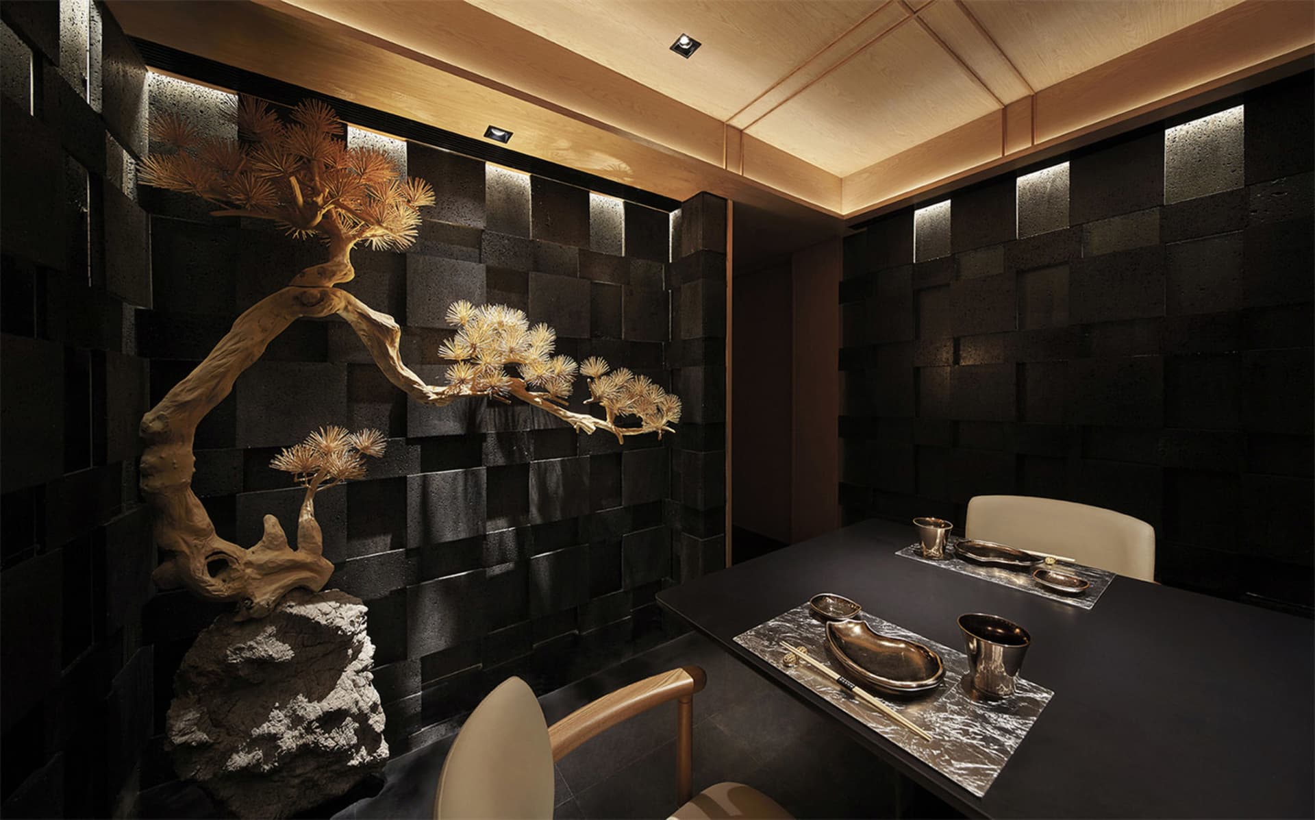 Elegant dining space with a wooden table, black tile floor, and stone wall, featuring Asian-inspired decor and a warm atmosphere