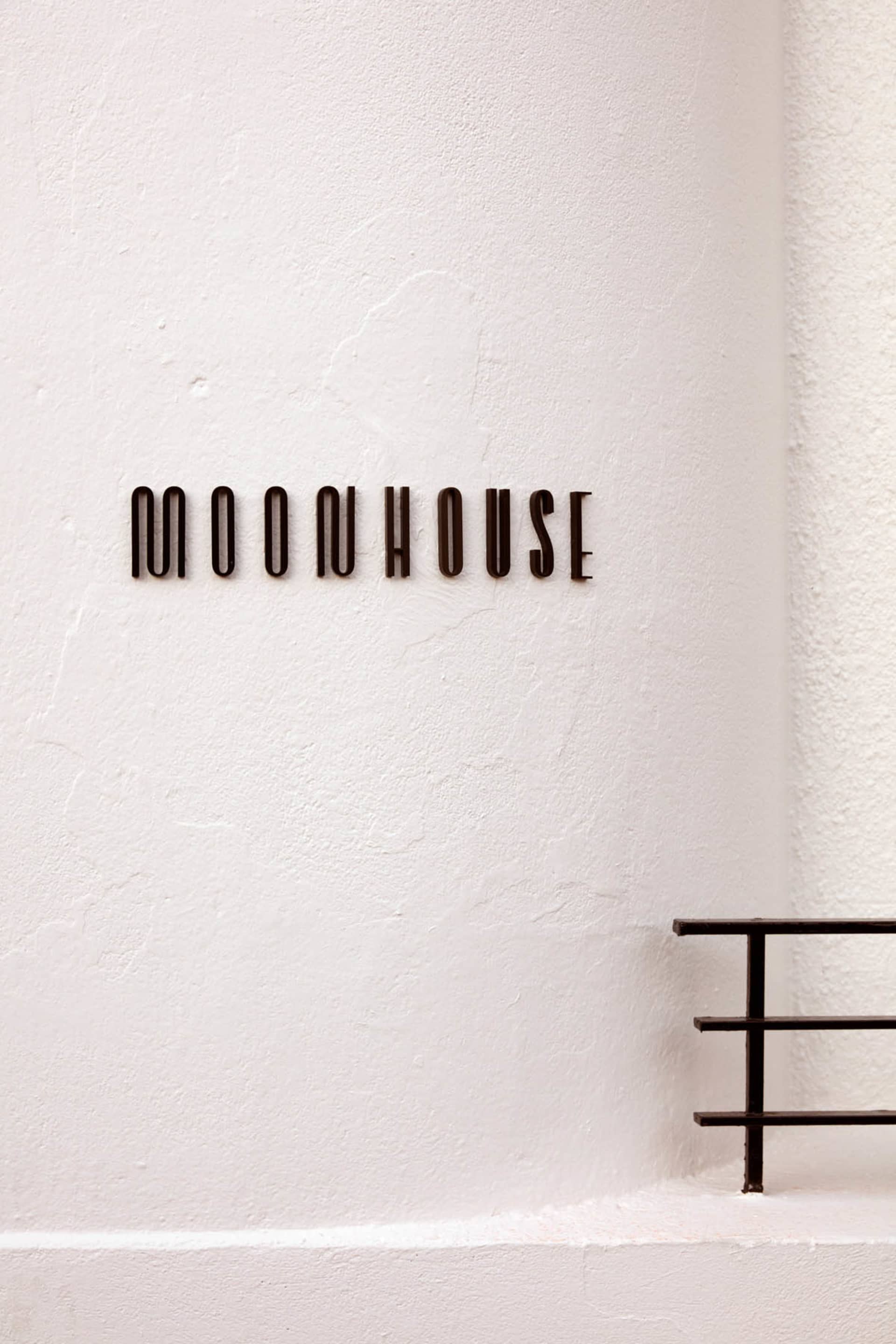 A white concrete building with a sign reading moonhouse, set against a blank background