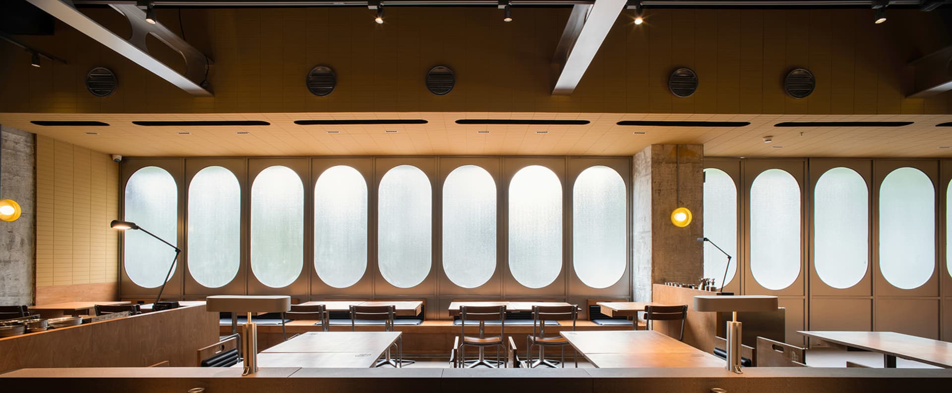 Open restaurant interior with multiple dining tables, wood elements, and comfortable seating options