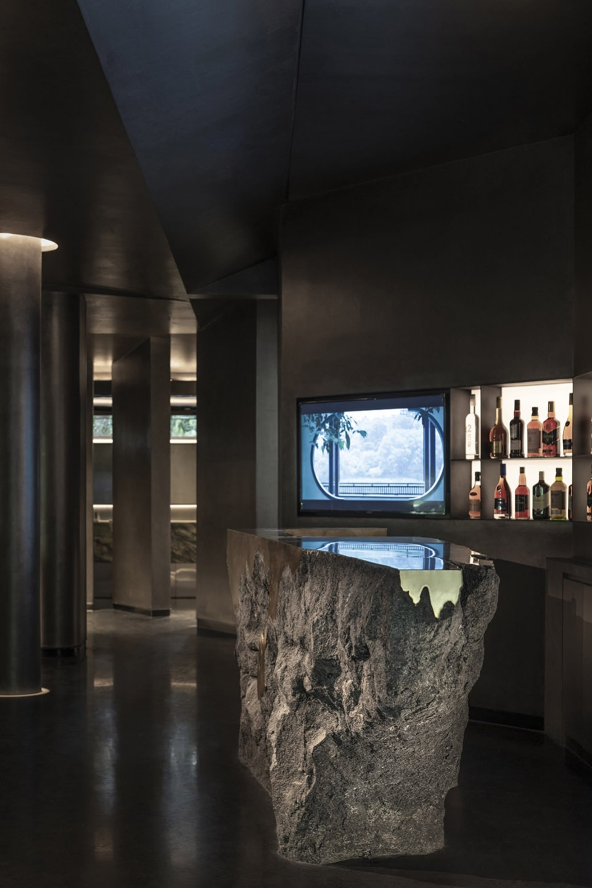 A modern interior design featuring a stone countertop, bar area, and bottles displayed on the countertop