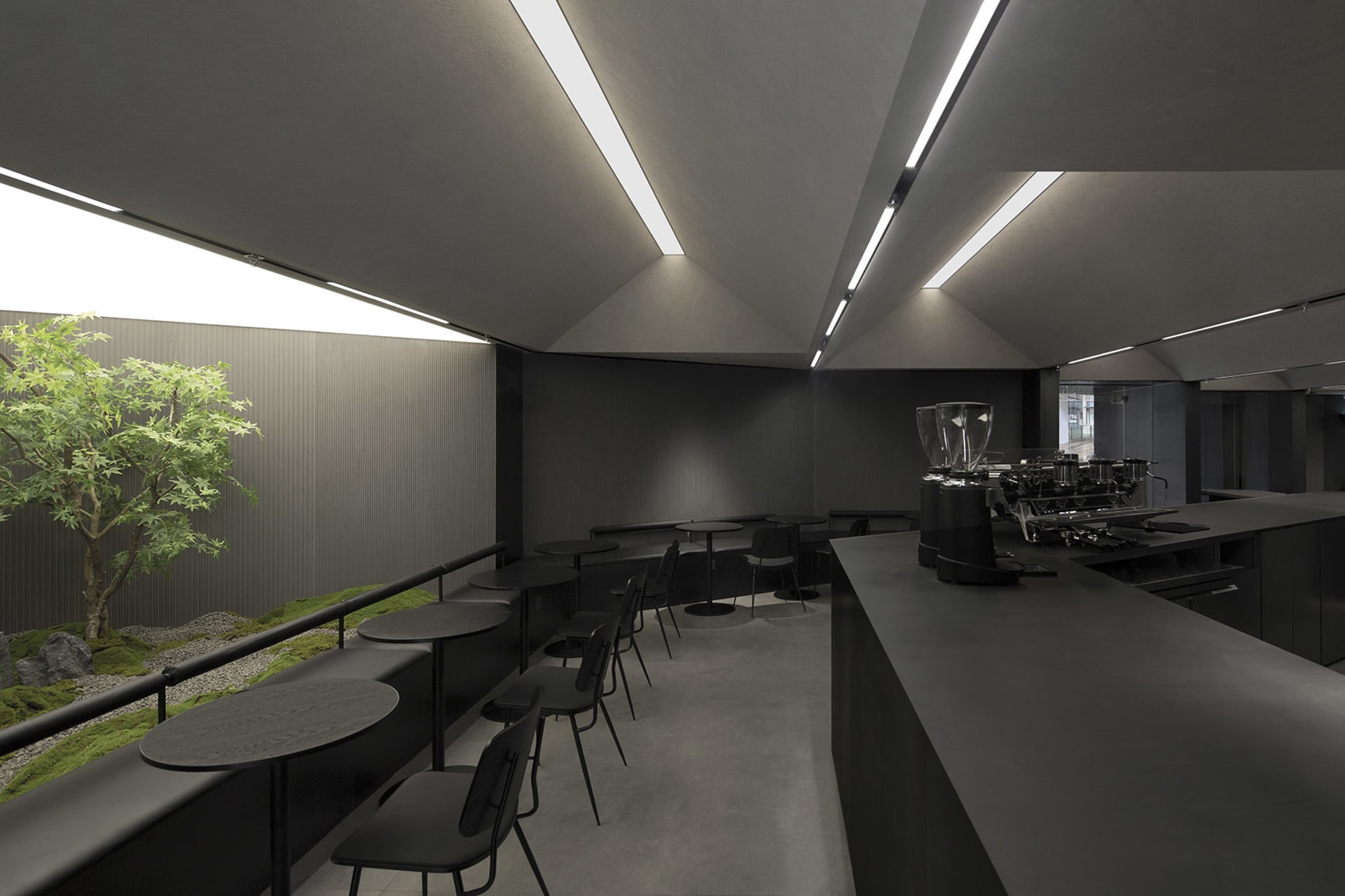 Empty dark restaurant interior with black walls and tables, chairs placed around the dining area