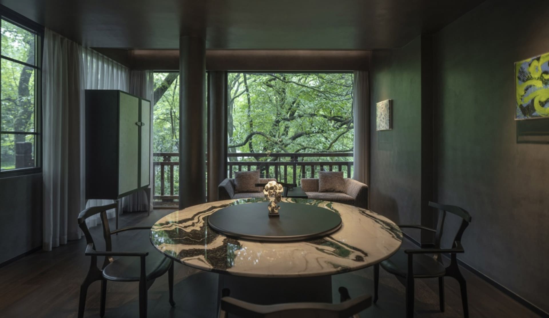 A luxurious living area with a marble table, chairs, a dining table, and a painting on the wall, exuding elegance and comfort