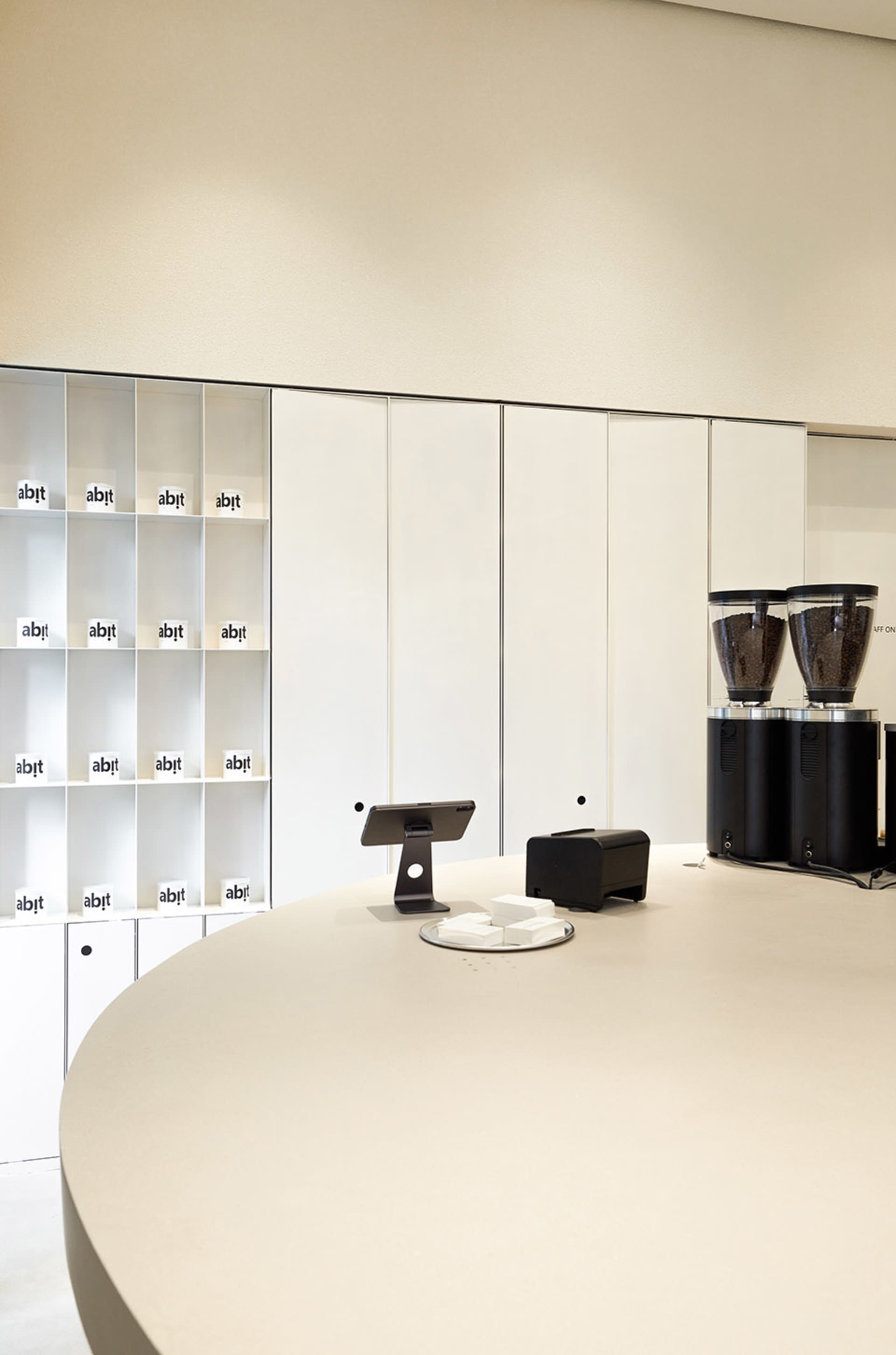 Office space with white walls and cabinets, featuring two black coffee makers and three cups on a countertop