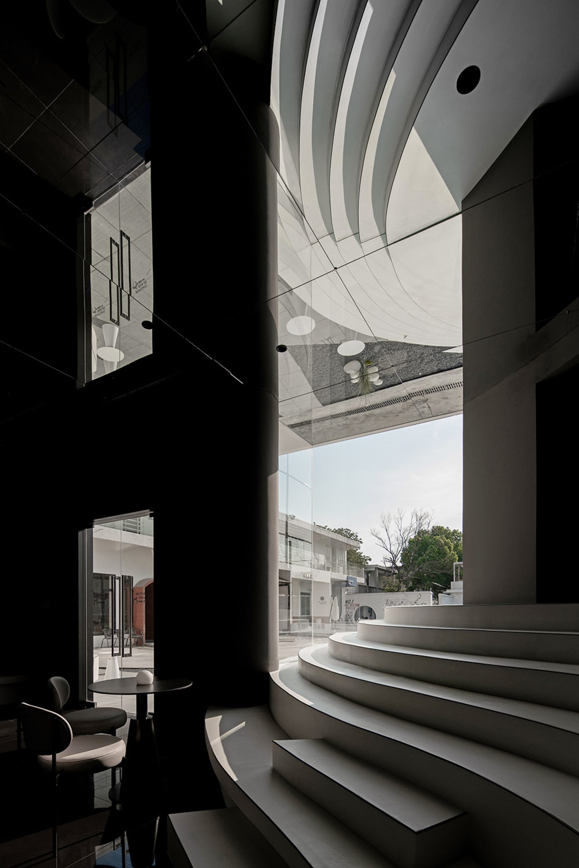 A dark interior space with a staircase leading to a balcony area, featuring multiple chairs and a mysterious atmosphere