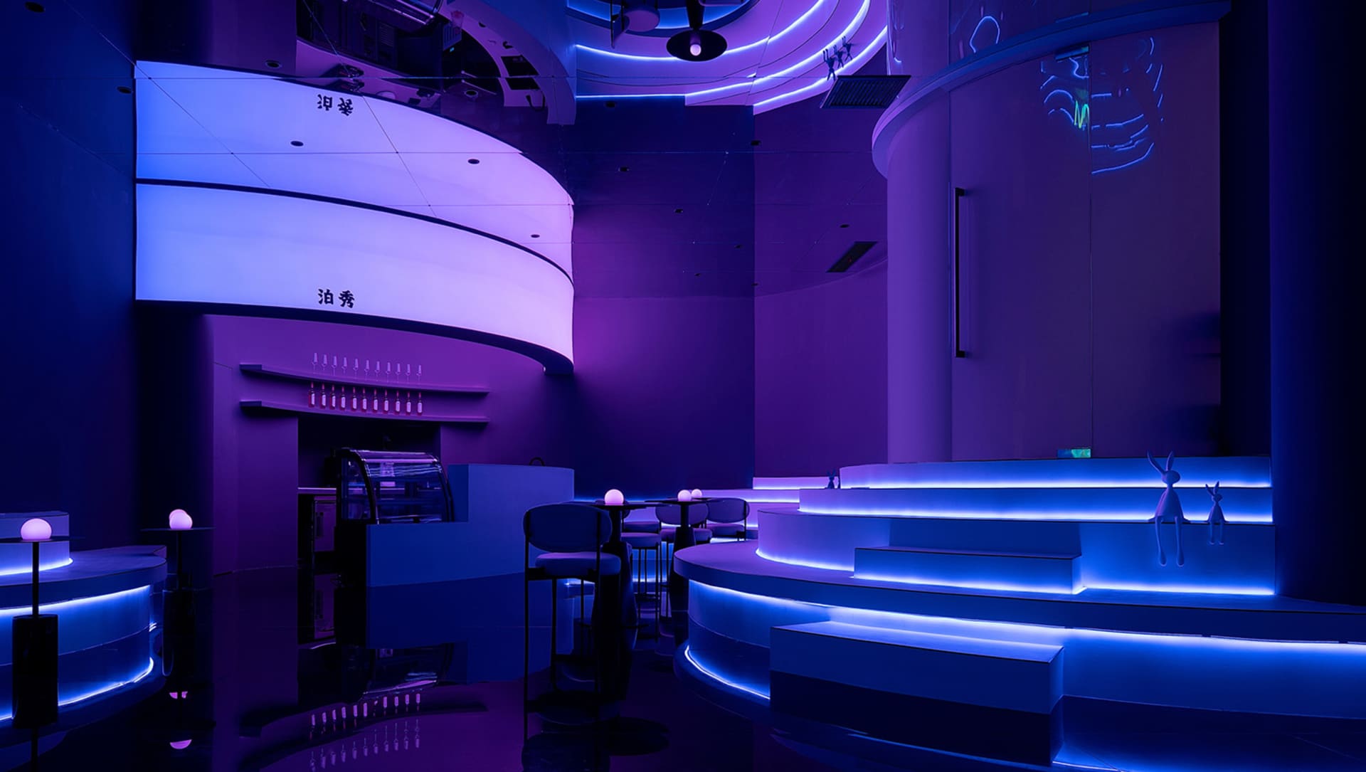 A modern restaurant with a purple ambiance, featuring chairs and dining tables in a stylish and comfortable setting