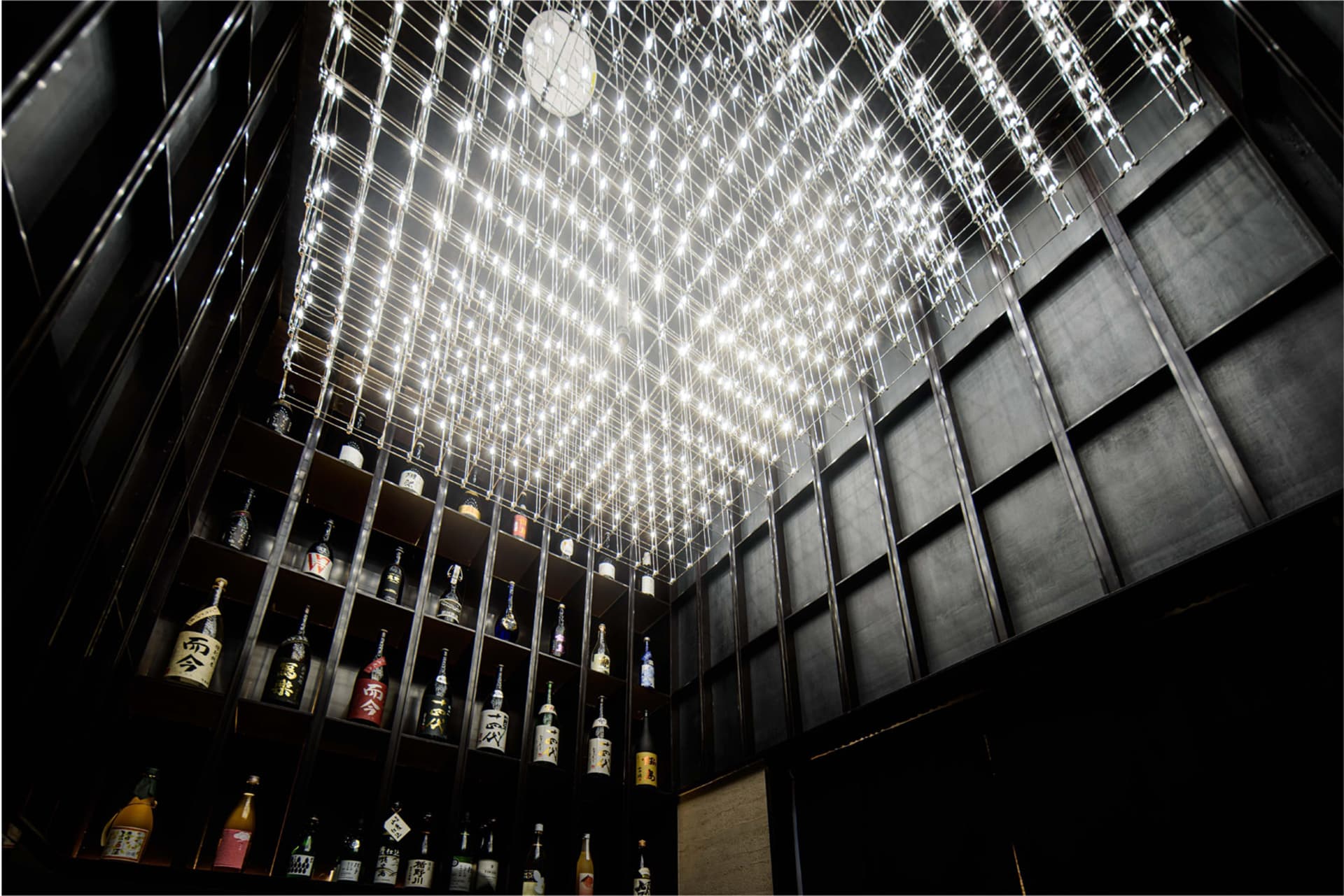 A cozy bar area with a large number of bottles displayed on shelves in various positions, creating an interesting arrangement