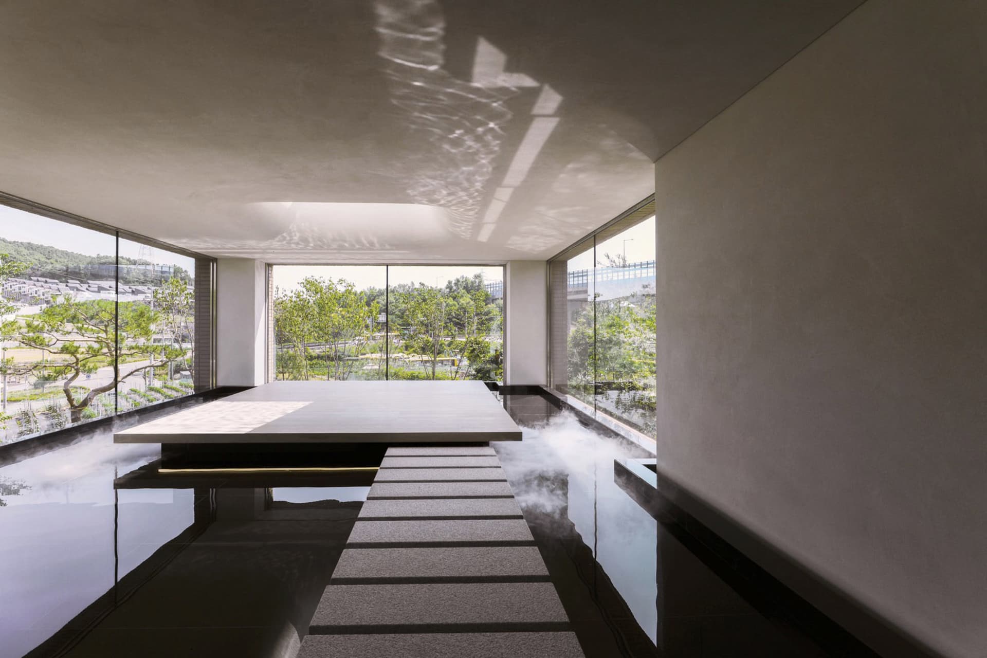 A modern indoor pool area with a staircase, potted plants, and a focus on relaxation and leisure