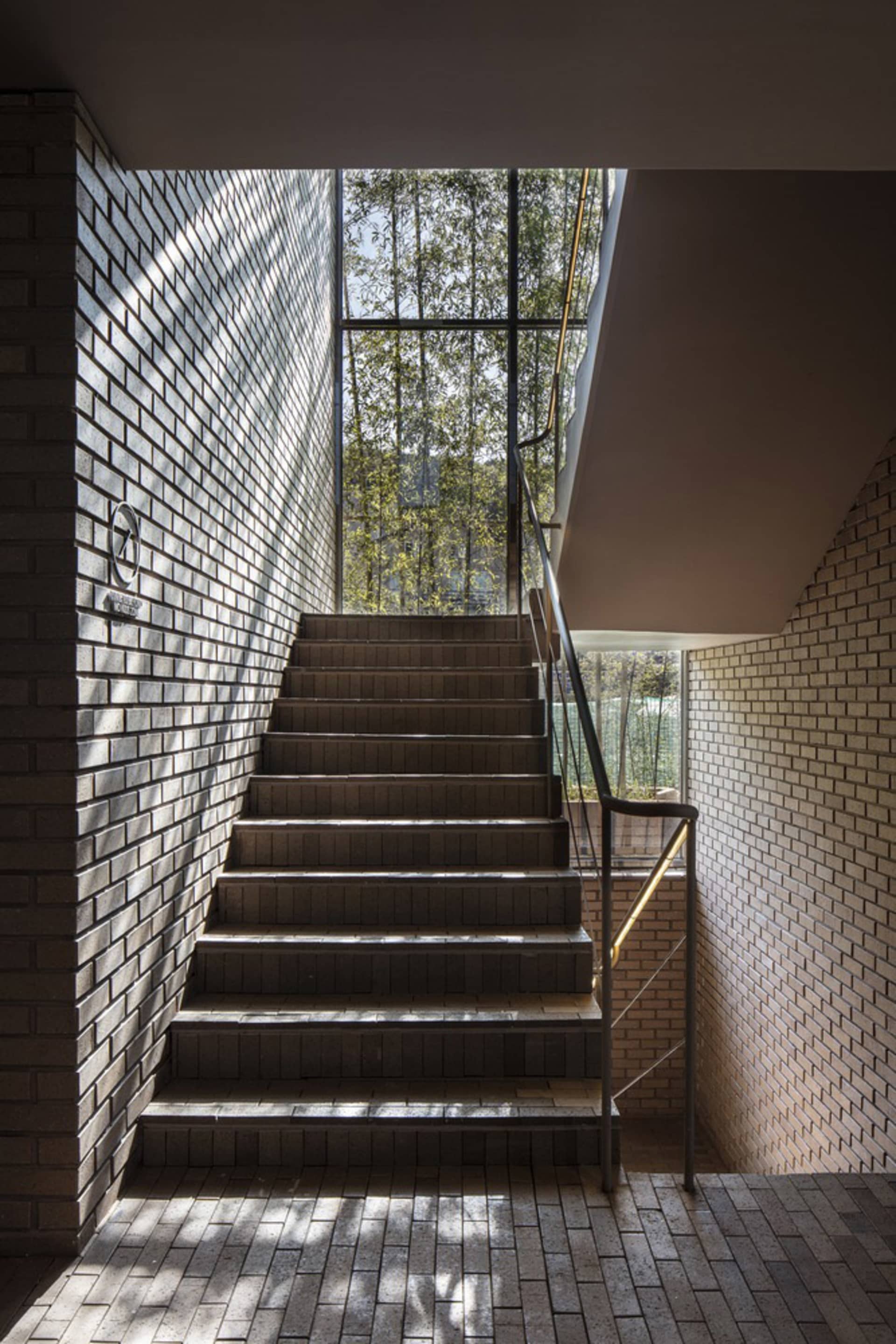 A rustic staircase with brick steps and a window on one side, surrounded by a sense of depth and dimension within a building