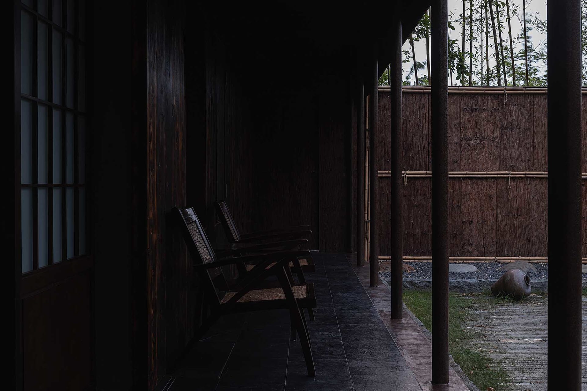 A calm and inviting indoor space with a bench in front of wooden pillars, creating a cozy seating area