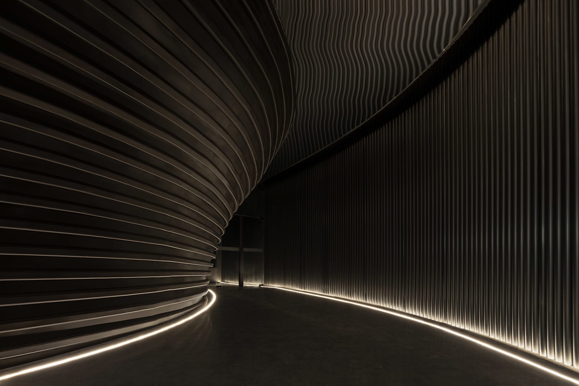 A calm and inviting interior hallway with a curved design, marble flooring, and two people standing near the center