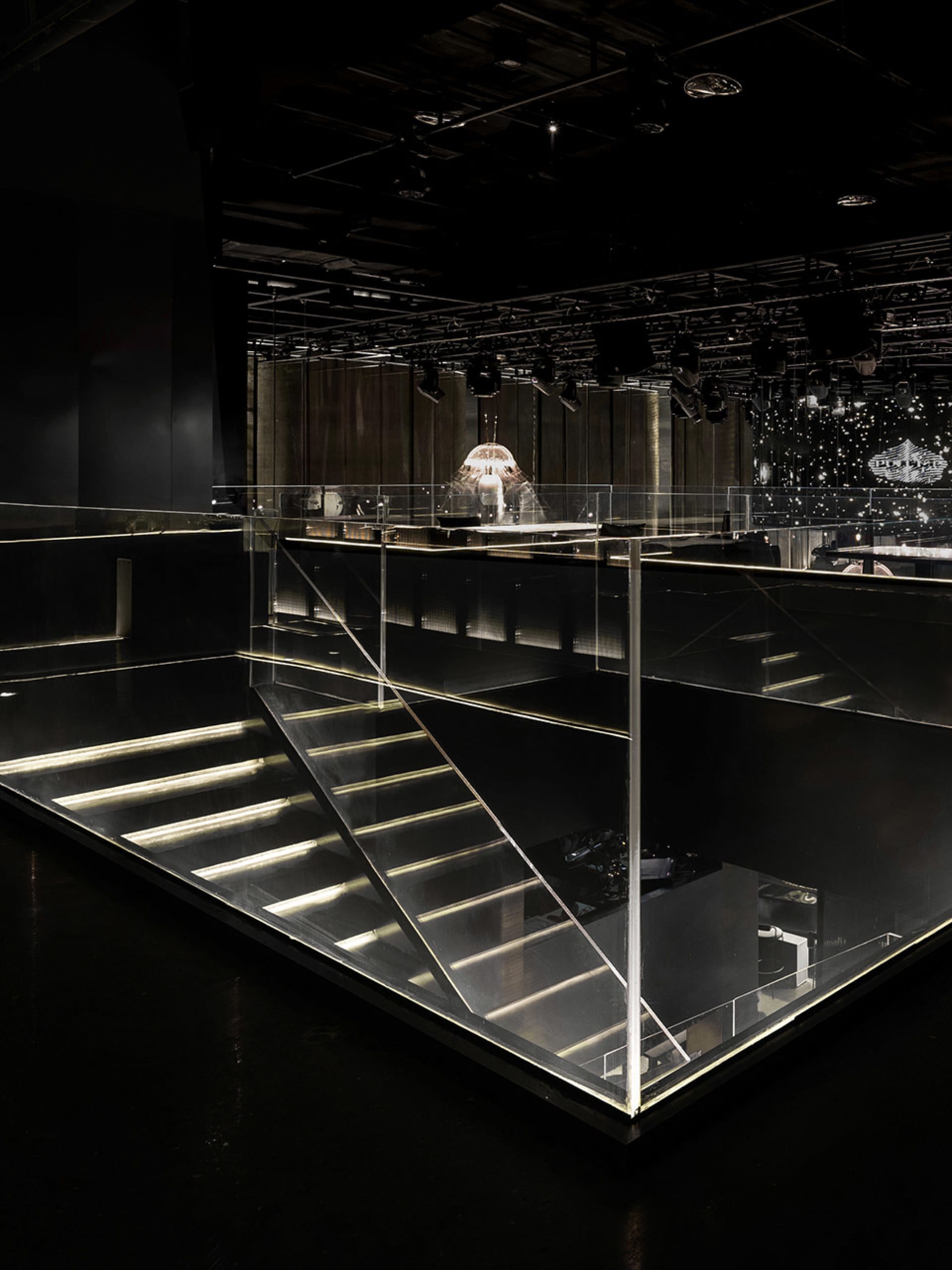 A modern staircase in a club or venue with a glass staircase and a minimalist design, shot in black and white
