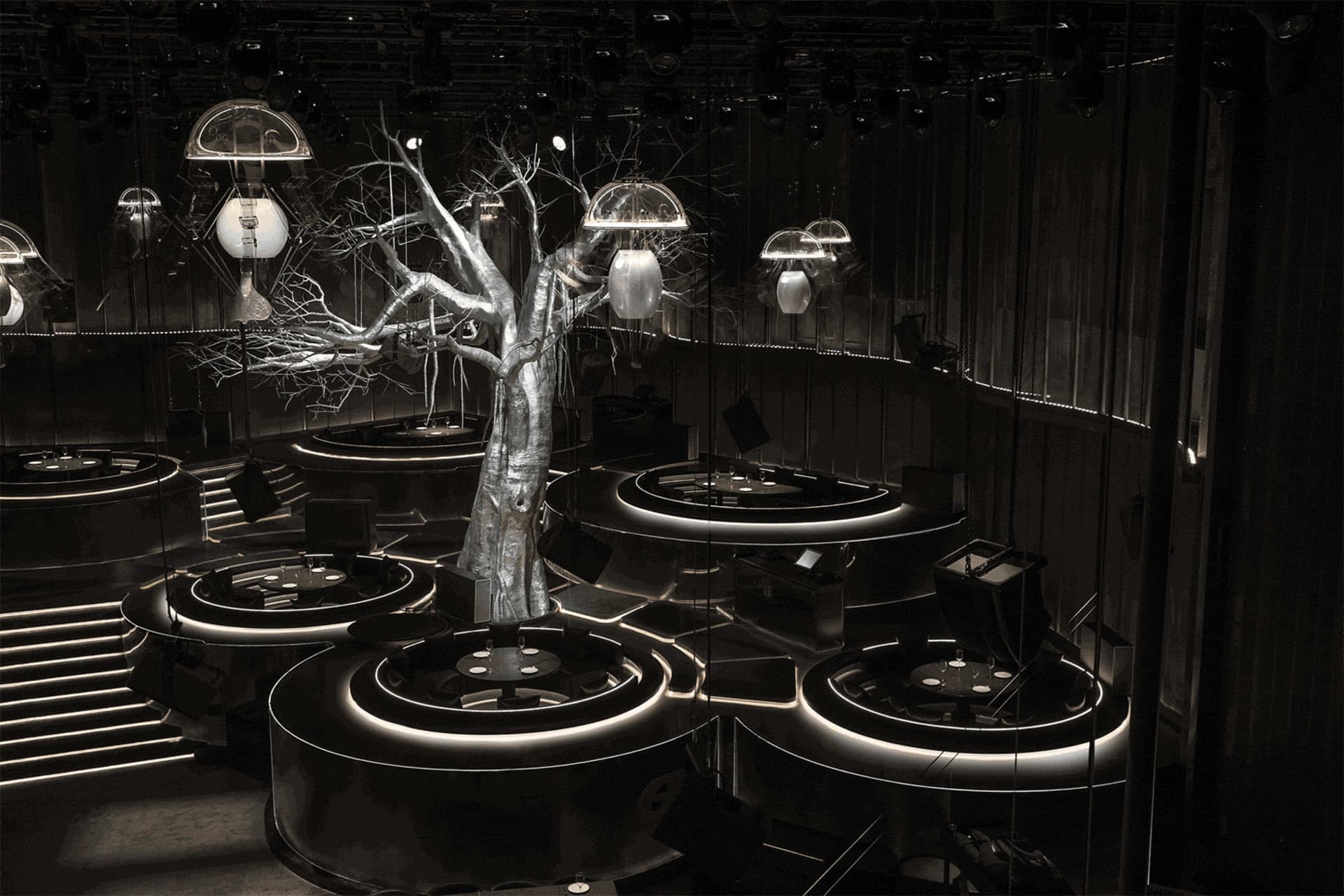 A modern dining space with a tree in the center, surrounded by a dining table and chairs, with clean lines and minimalist design elements, well-lit by natural or artificial light