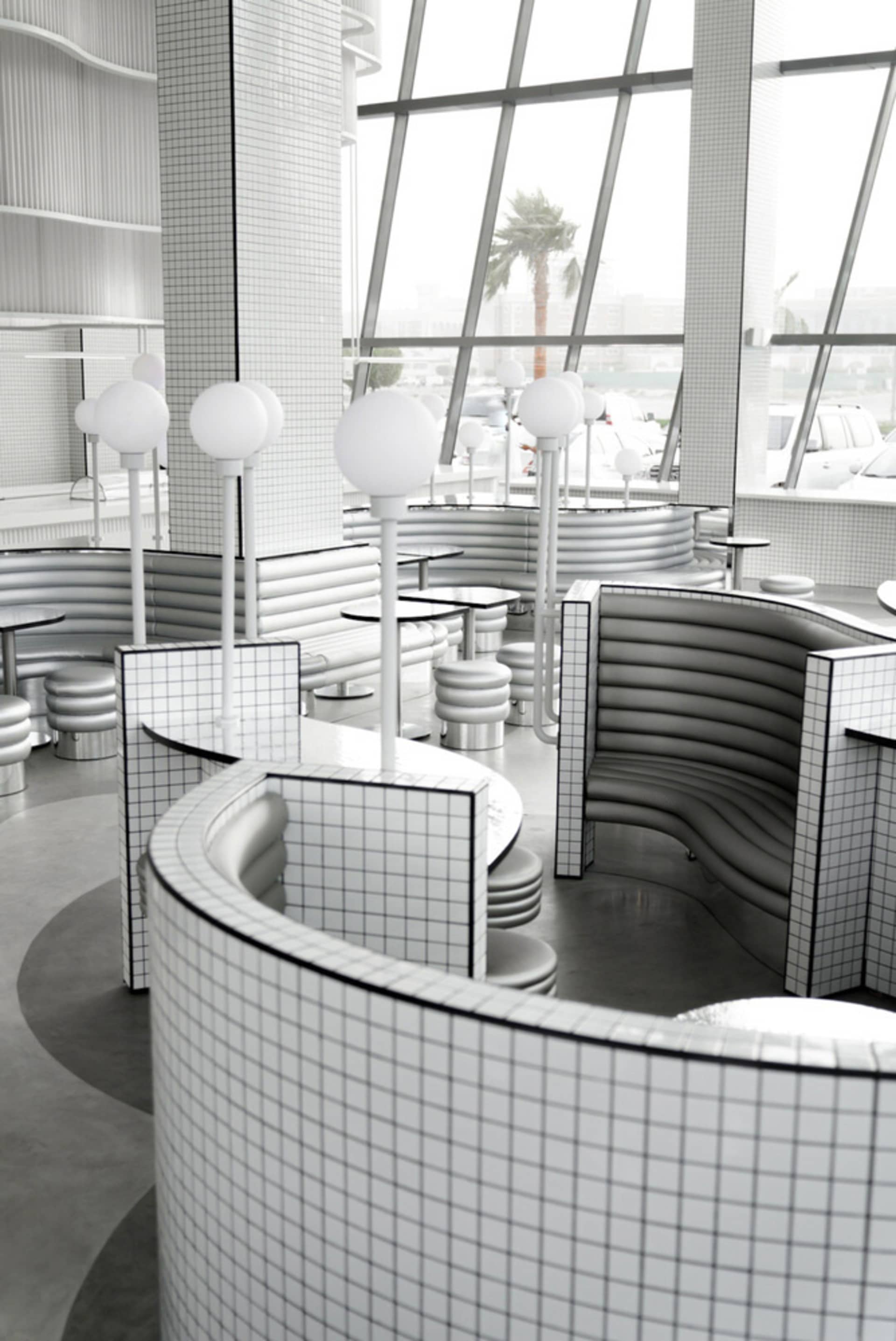 Modern restaurant interior with a circular dining area, metal booths, and chairs, surrounded by a clean and inviting atmosphere