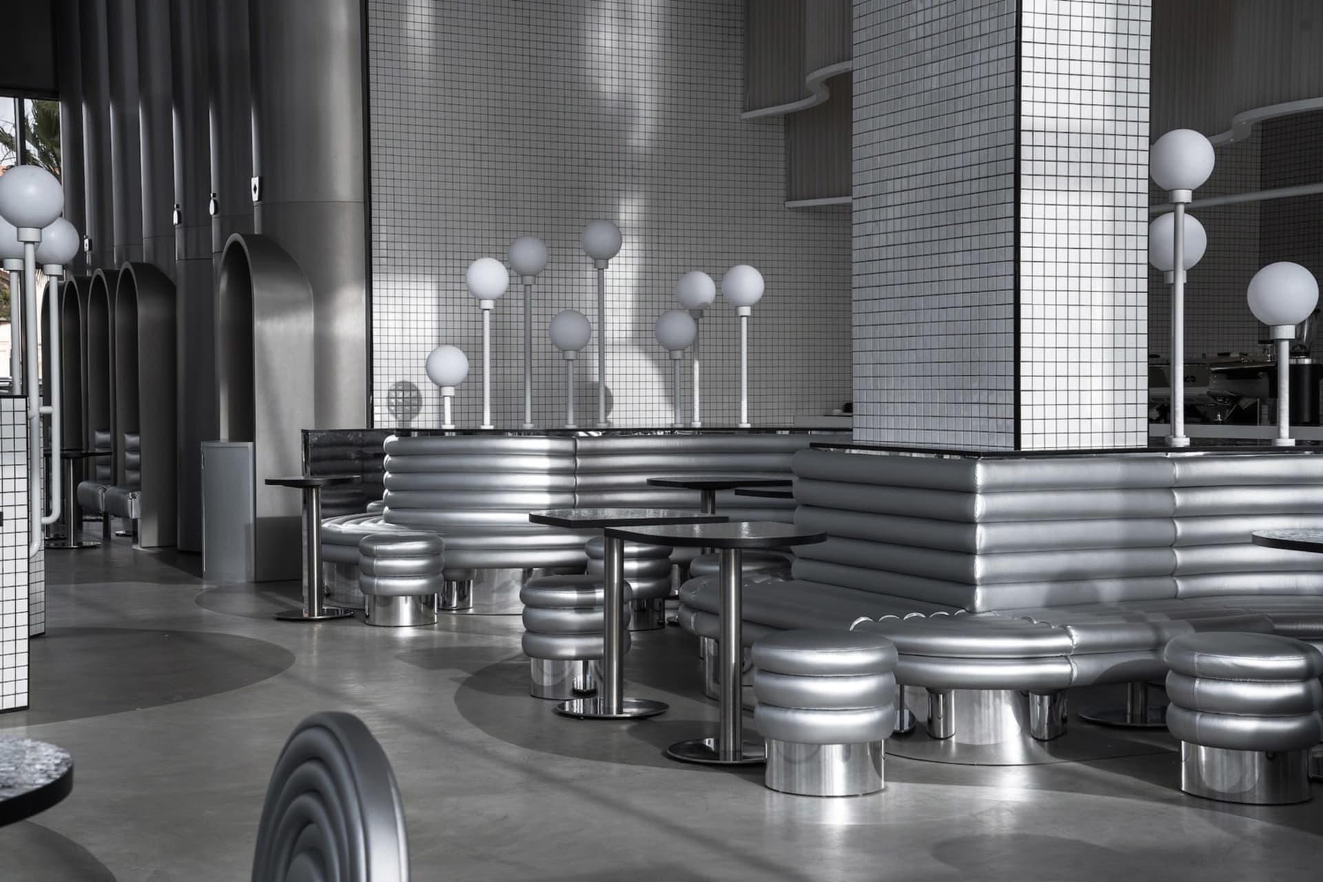 Modern restaurant interior with multiple tables, benches, and tiled walls, creating a clean and inviting atmosphere