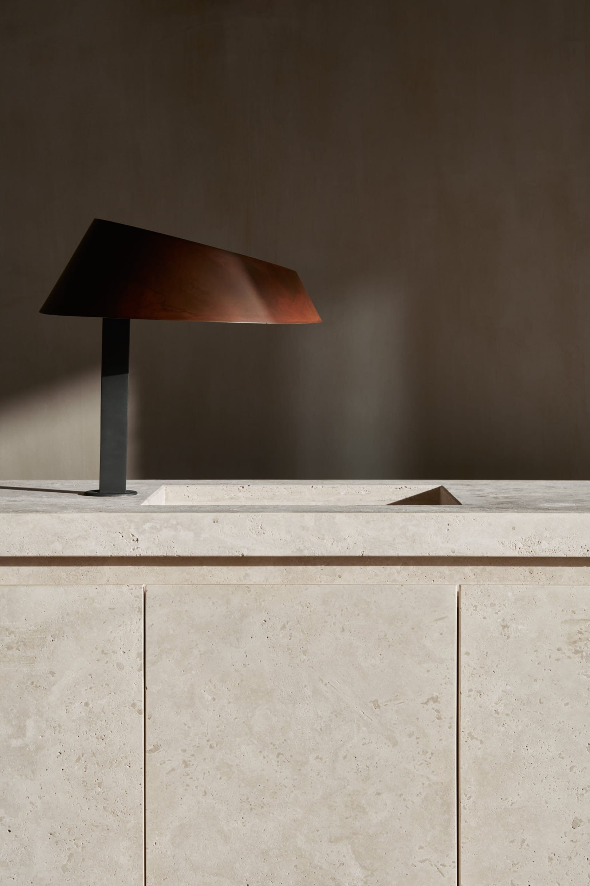 A modern room with a wooden lamp on a marble countertop, set against a white-painted wall