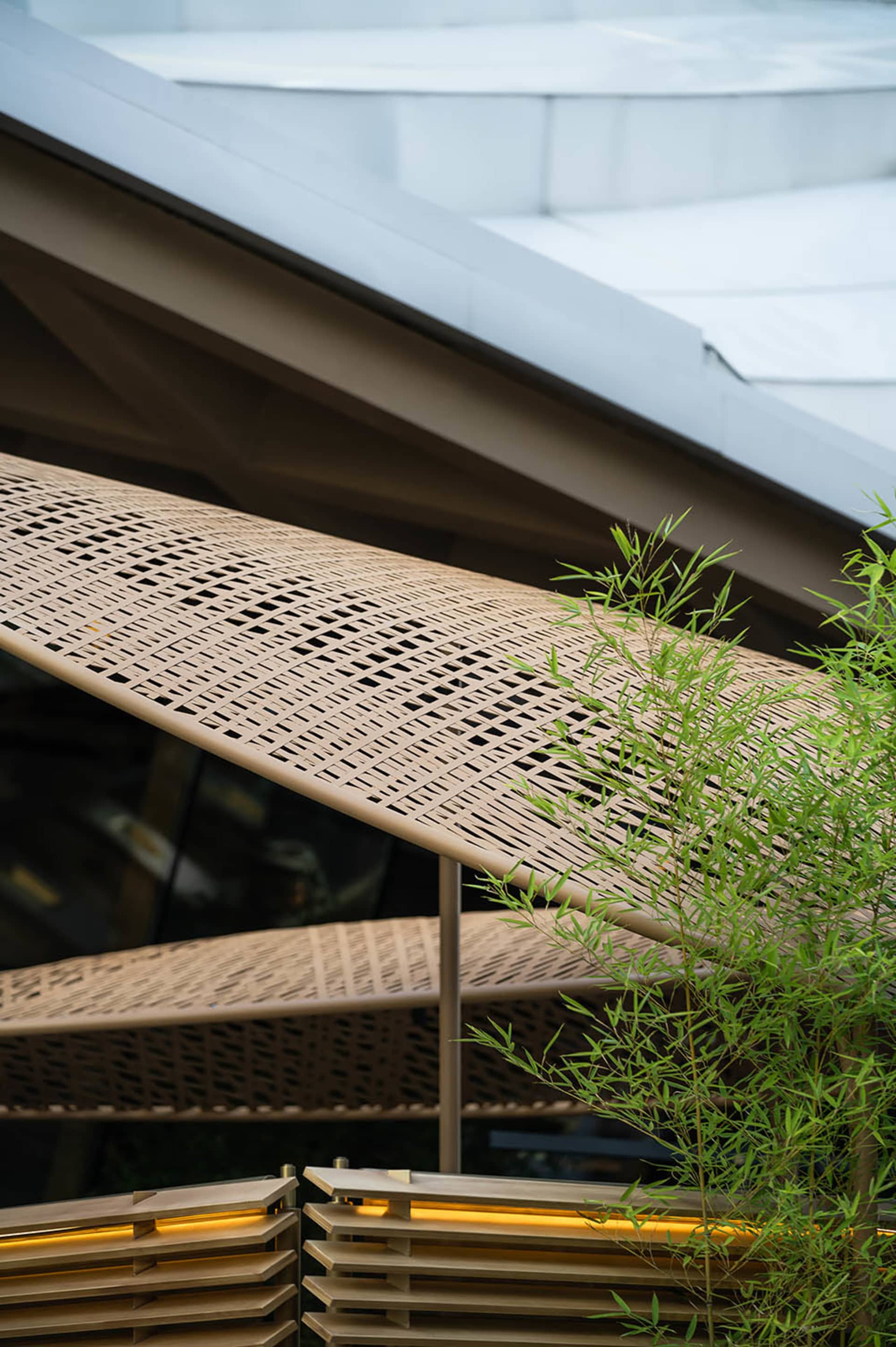 A rustic building with a wooden facade, a large overhang, and a unique roof design, featuring two umbrellas and a car parked underneath