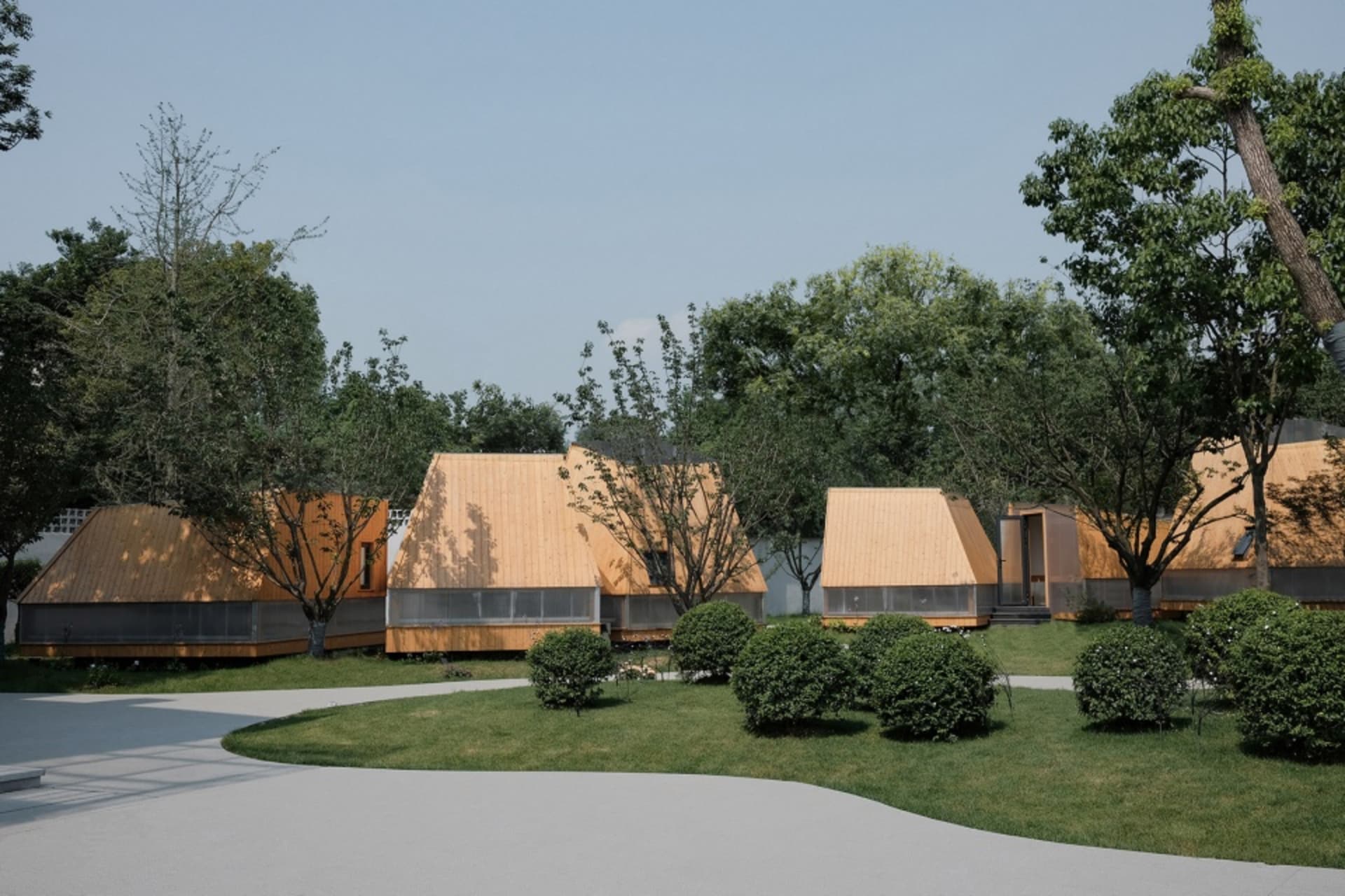 A serene village scene with small wooden houses in a grassy area, each with its own unique design and style