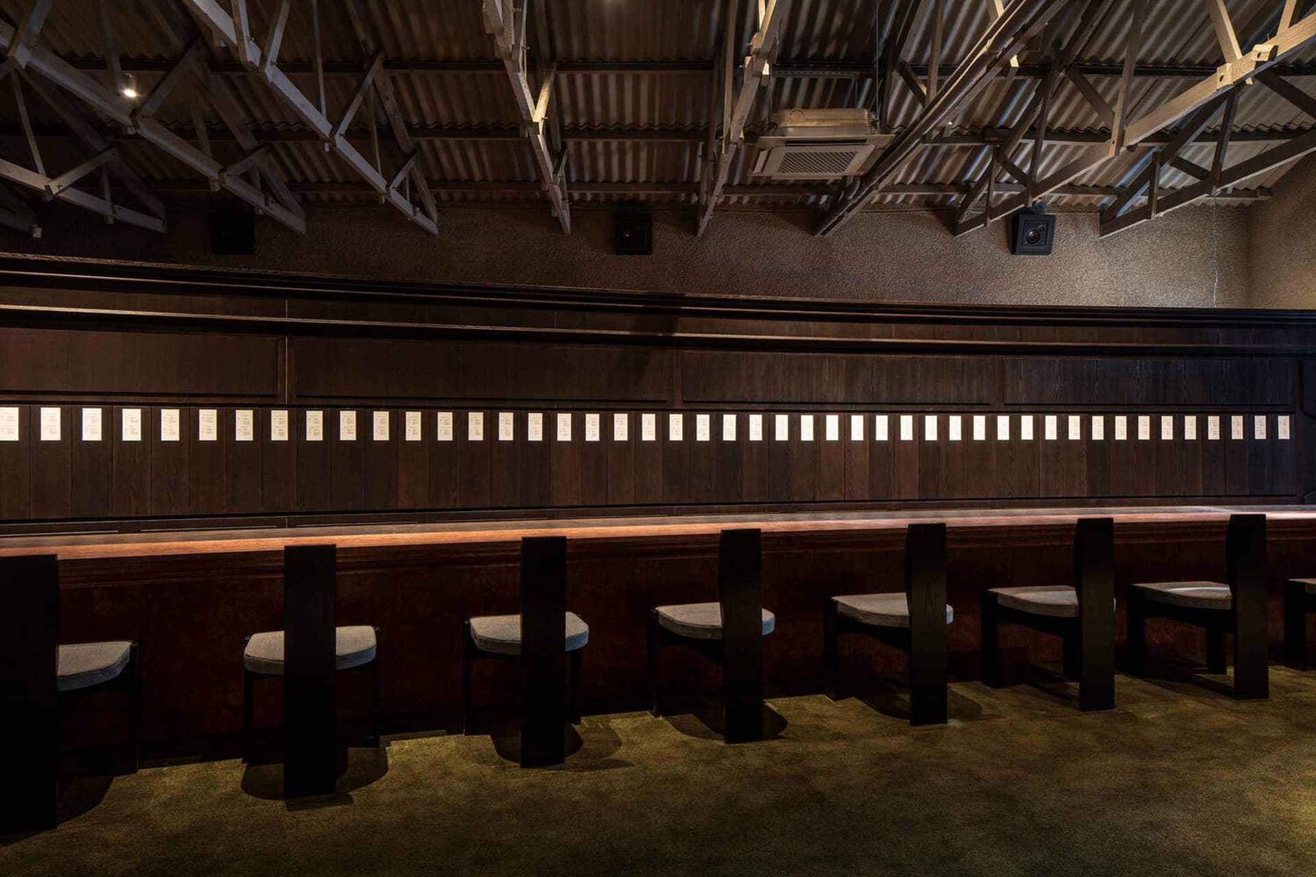 Cozy indoor bar area with wooden walls and tables, featuring a dining table and chairs, creating a warm and inviting atmosphere for socializing and enjoying drinks