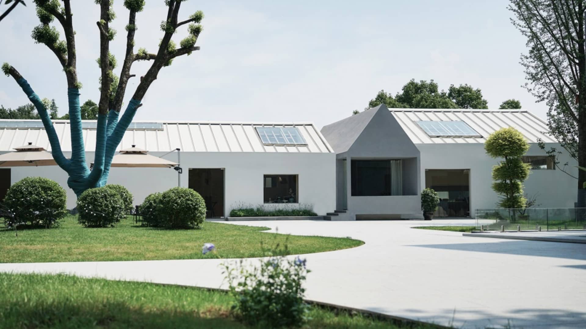 A modern house with a white exterior, featuring multiple rooms with large windows for natural light, minimalist decor, and a focus on functionality