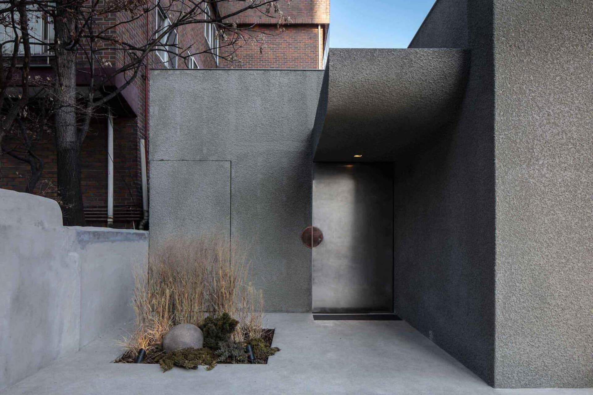 Exterior view of a modern building with a doorway and two windows, one on each side, with natural light present