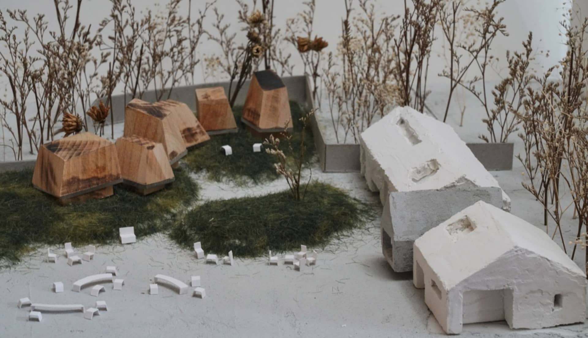 A diorama featuring a rustic village with wooden houses, cabins, and trees, arranged in a model display