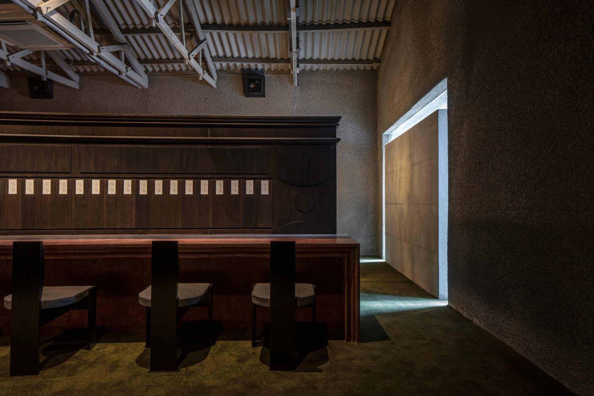 A cozy bar area with three wooden chairs, a wooden countertop, and a doorway leading outside