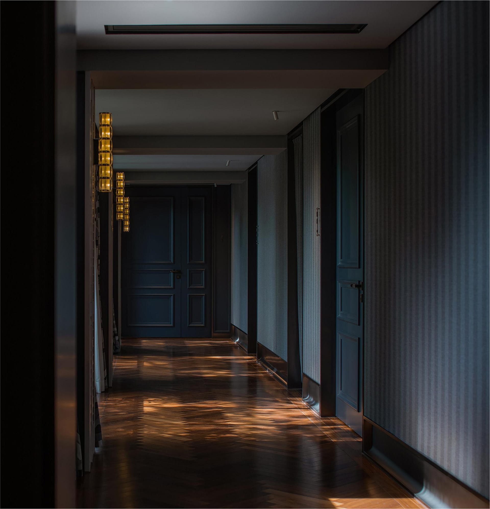 A dimly lit hallway with wooden floors and walls, featuring two doors on either side
