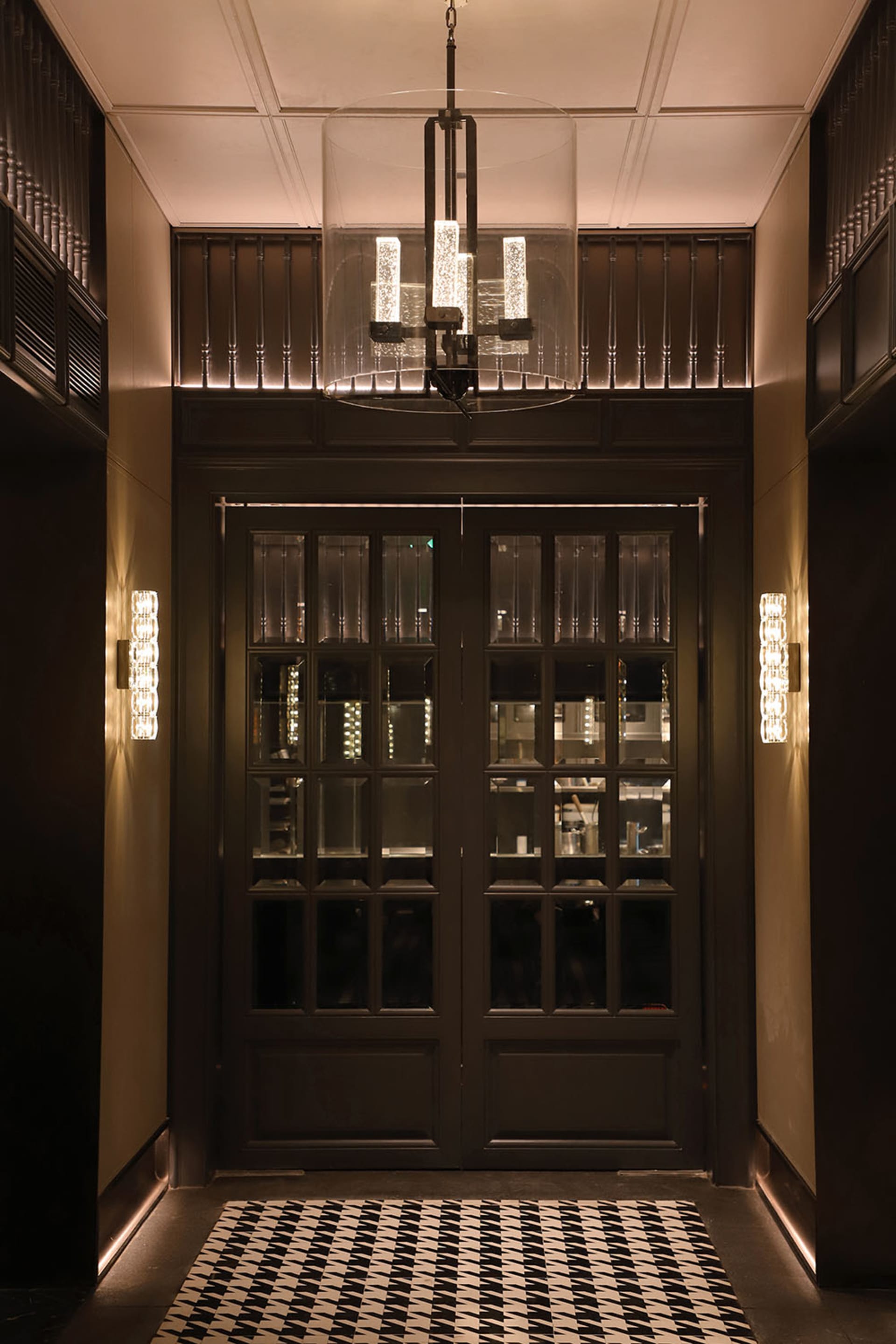 Elegant restaurant interior with a glass doorway, chandelier, and inviting atmosphere